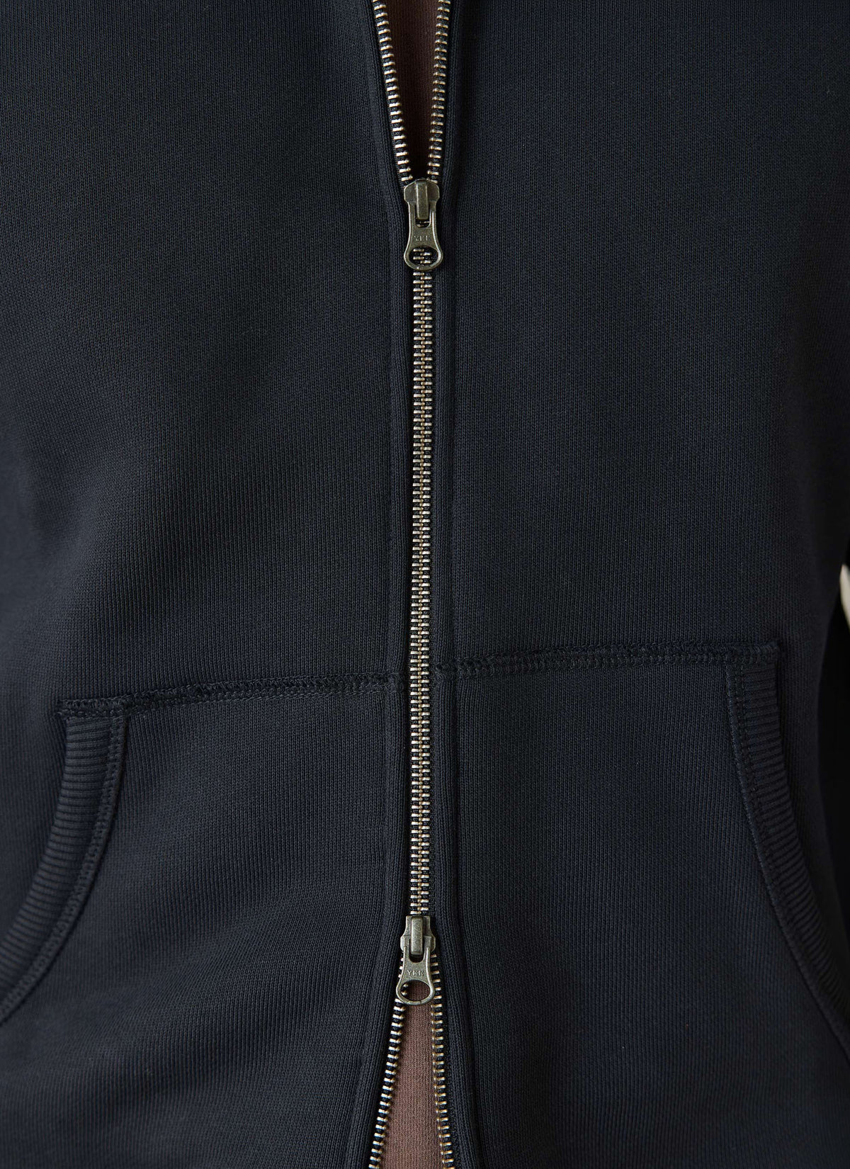 A close-up of the black Percival Chronicle zip hoodie in organic cotton, showing the two-way zip and front pockets.