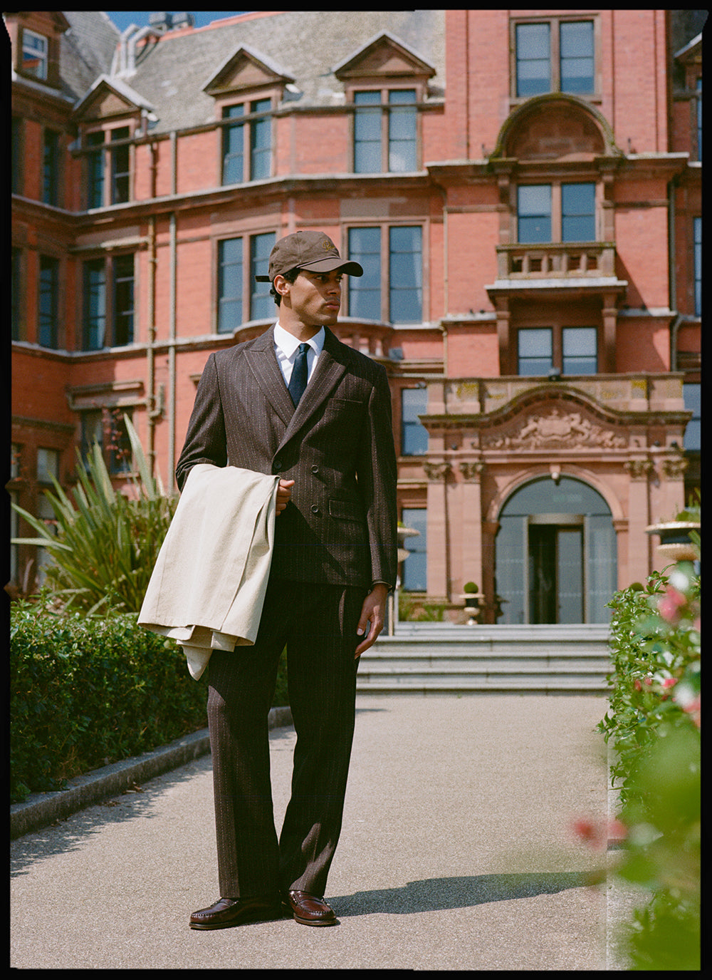Model wears Percival Clifton Pinstripe Double Breasted Blazer and Clifton Pinstripe Pleated Tailored Trousers in Espresso.
