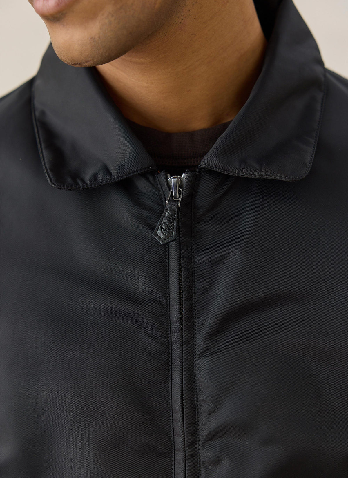 A close-up of the Percival black nylon collared bomber jacket showing the pointed collar and zipped front.