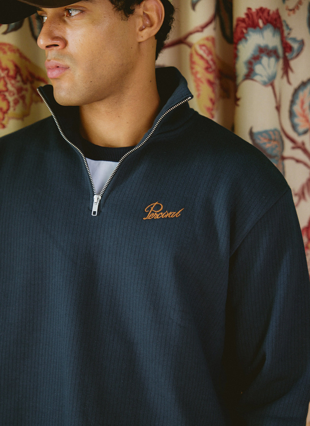 Close-up of a model wearing the navy Percival Conrad Funnel Neck 1/4 Zip Jumper in 100% cotton with an embroidered logo.