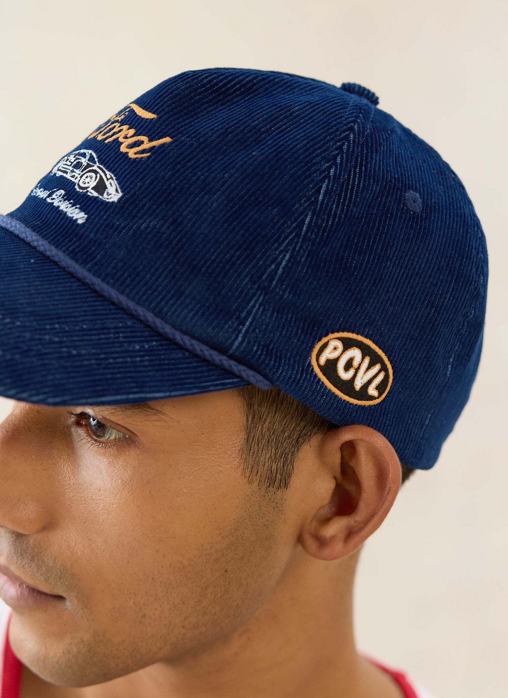 Navy Ford x Percival cord trucker cap featuring side PCVL embroidery and vintage racing artwork on the front.