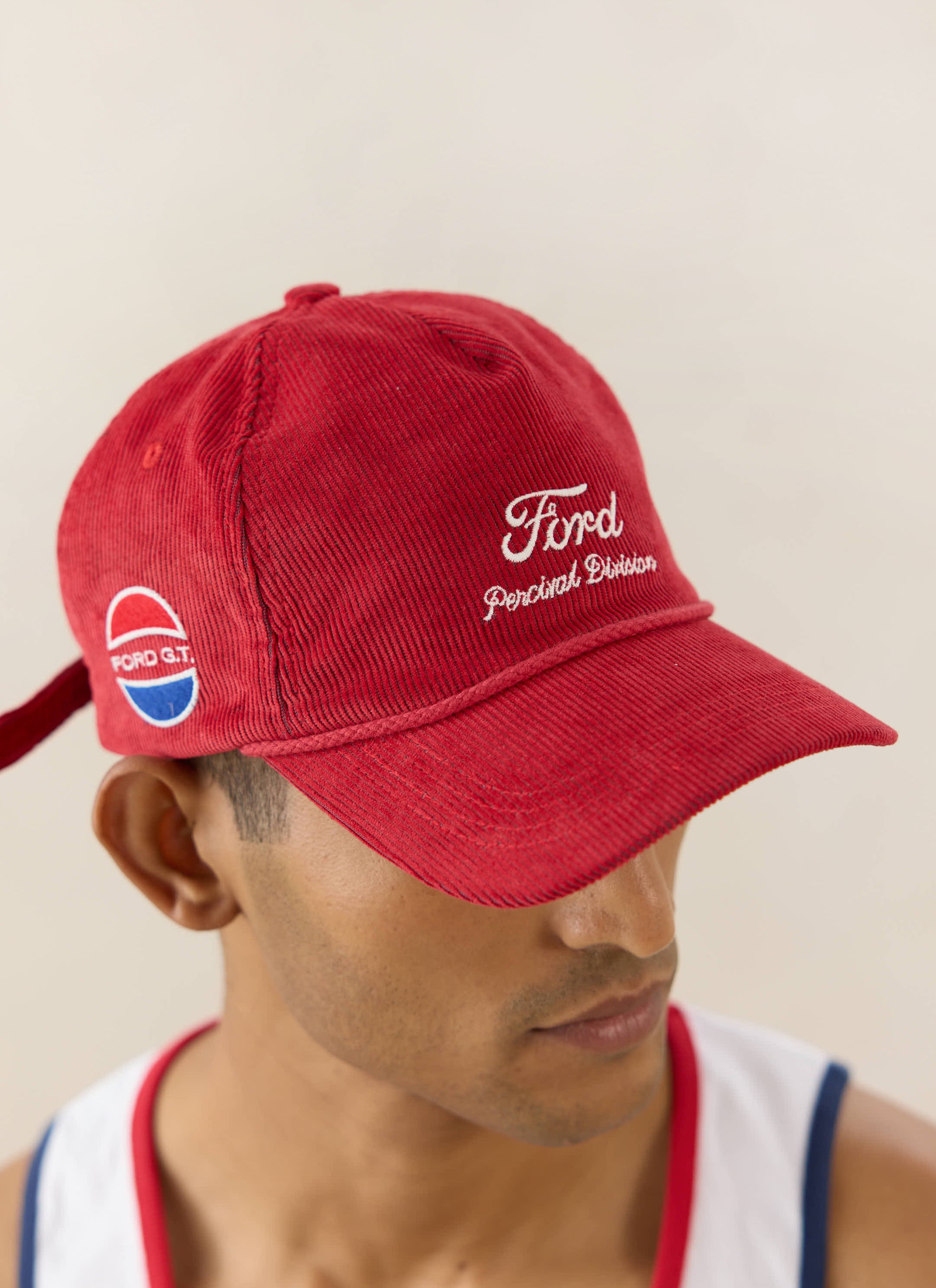 Red corduroy Ford x Percival trucker cap with white embroidery, styled on a model as part of the Ford collaboration.