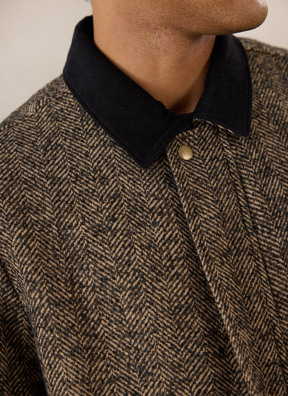 Close-up of a model wearing the brown herringbone wool cropped boxy jacket from Percival, highlighting the contrast collar.