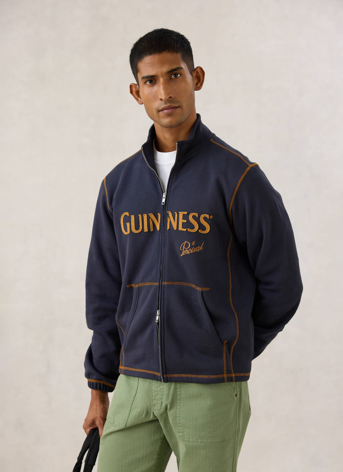 Model wearing the navy blue Guinness x Percival zip up sweatshirt with contrast stitching and appliqué branding.