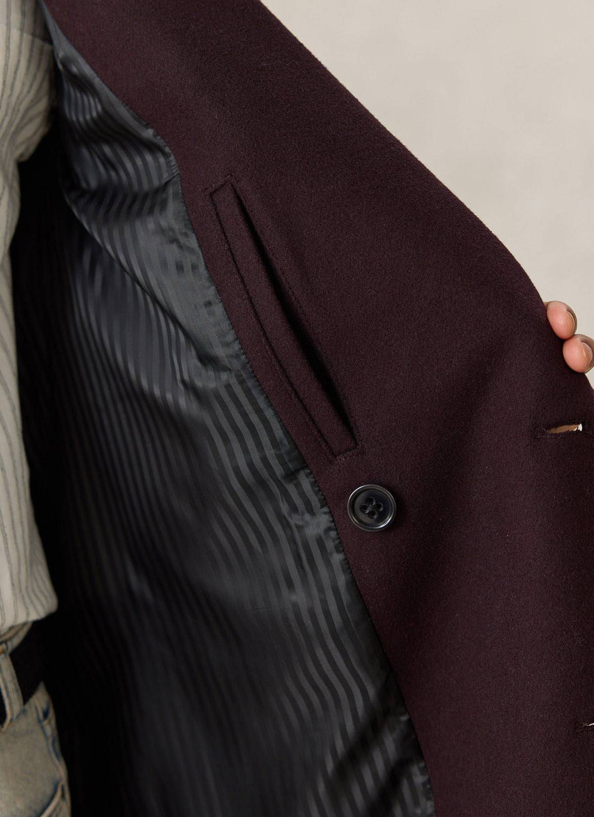 A close-up of the dark brown Percival wool-blend double-breasted overcoat, highlighting the chest welt pocket and button.