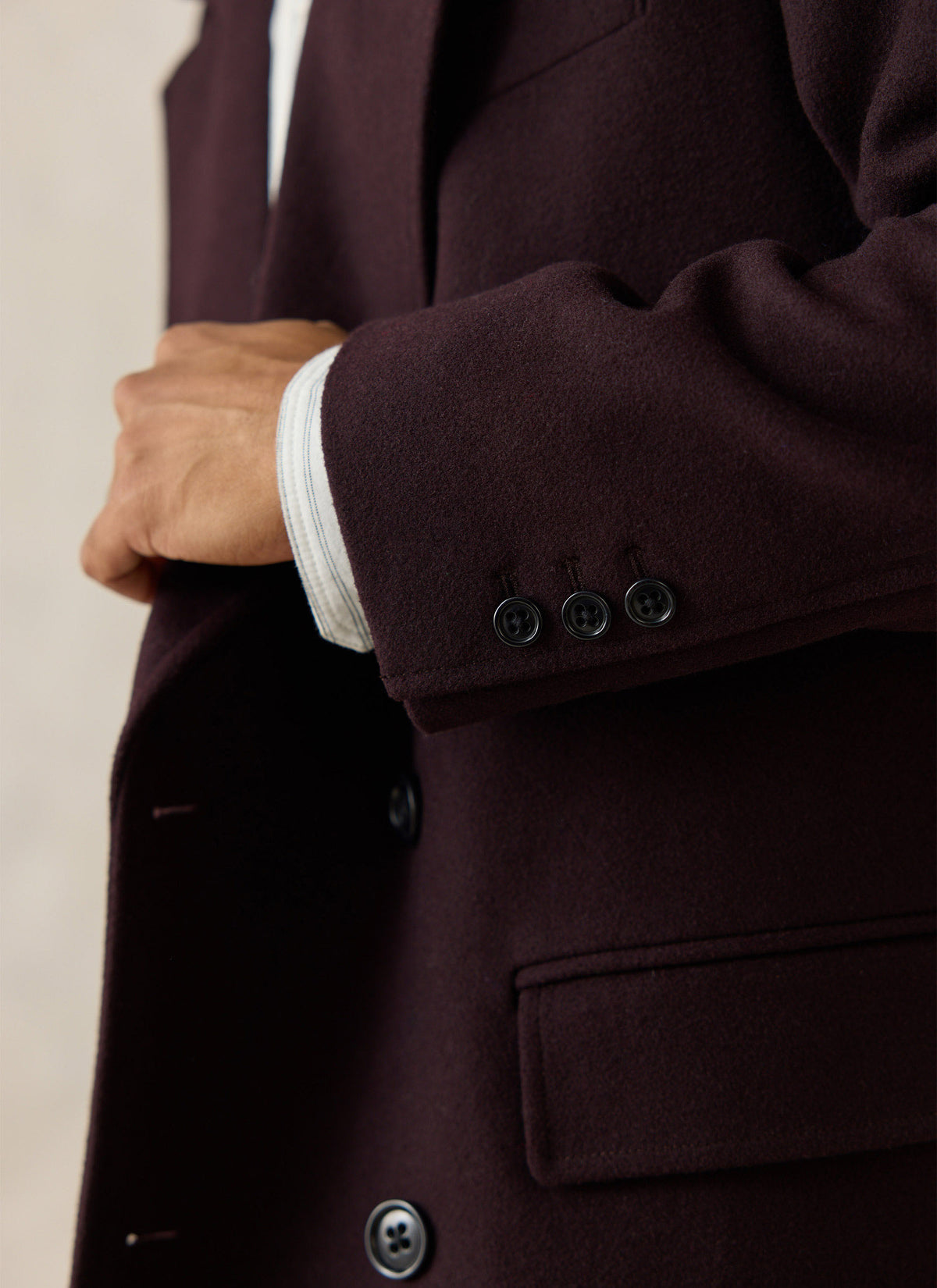 Close-up of the dark brown Percival wool-blend double-breasted overcoat, highlighting the sleeve buttons and flap pocket.