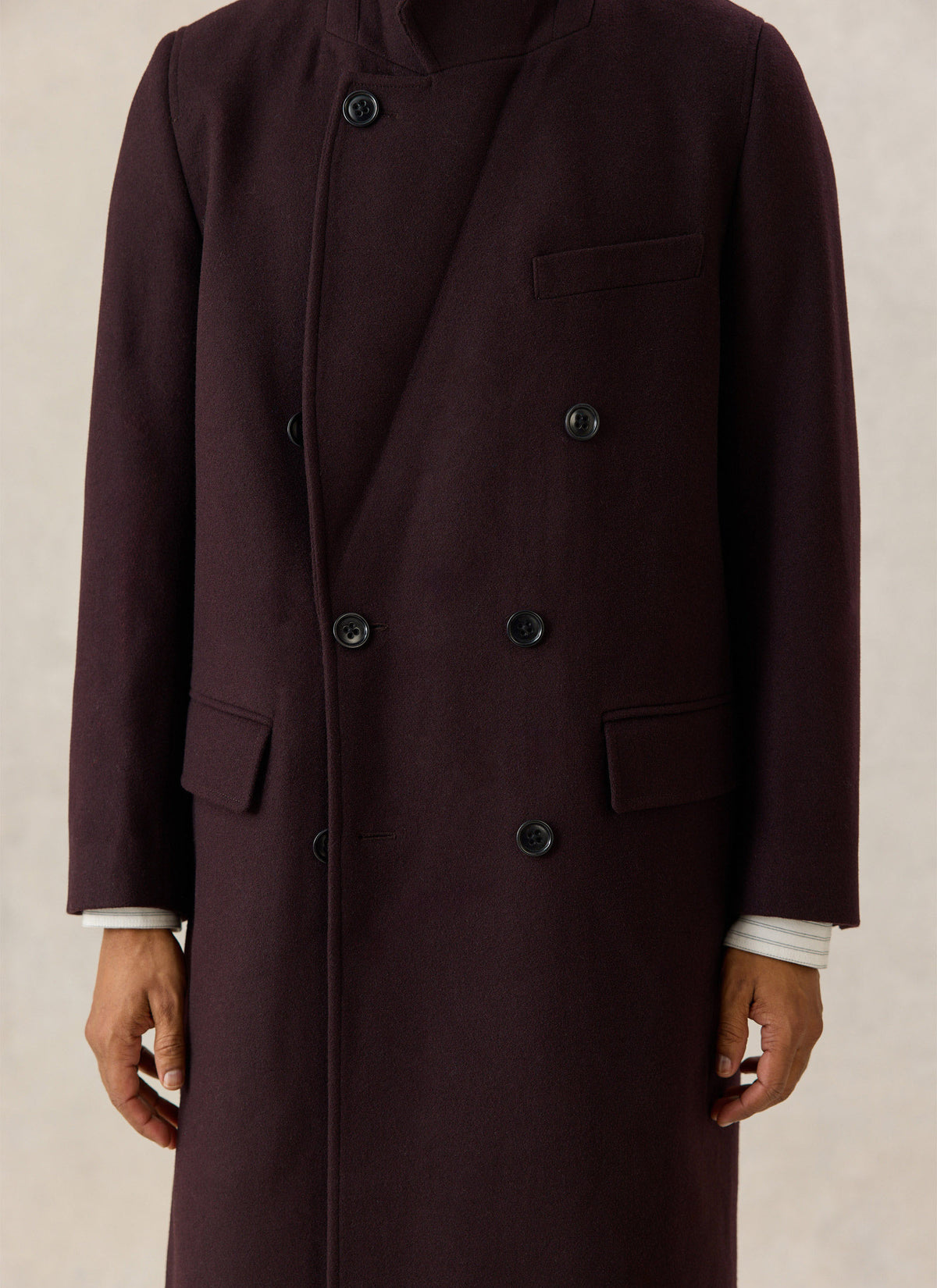 A close-up of the Percival dark brown wool-blend double-breasted overcoat, highlighting the button closure and pockets.