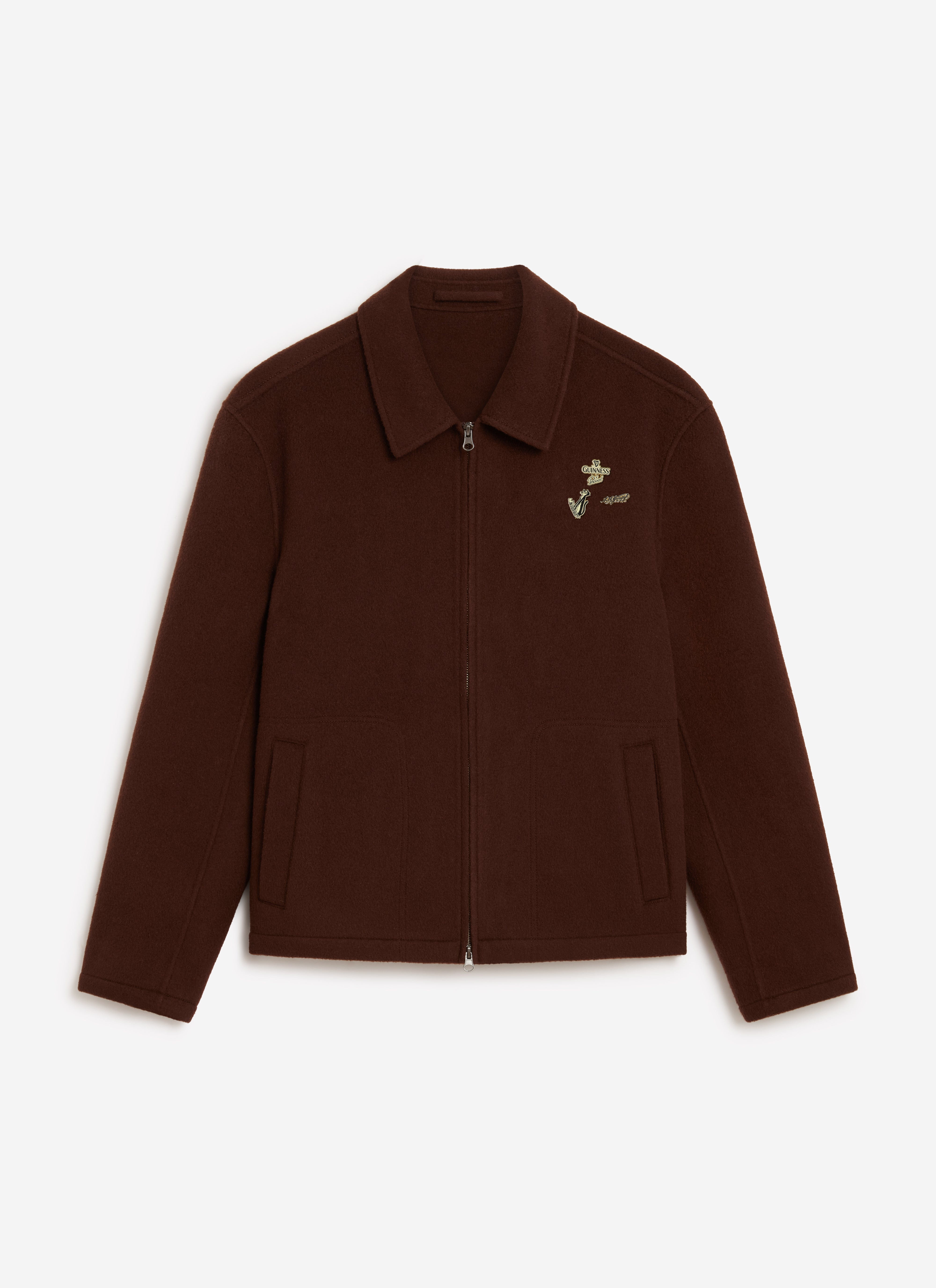 The Percival x Guinness wool jacket in espresso brown, shown flat with its collaboration pin badges on the chest.
