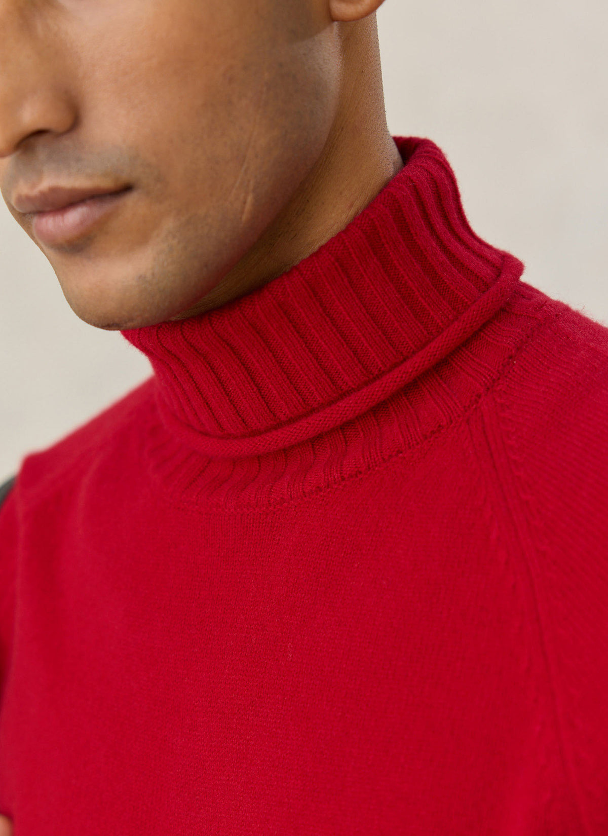 A close-up of the red Percival Dylan 100% wool roll neck jumper, highlighting the ribbed collar and raglan sleeves.