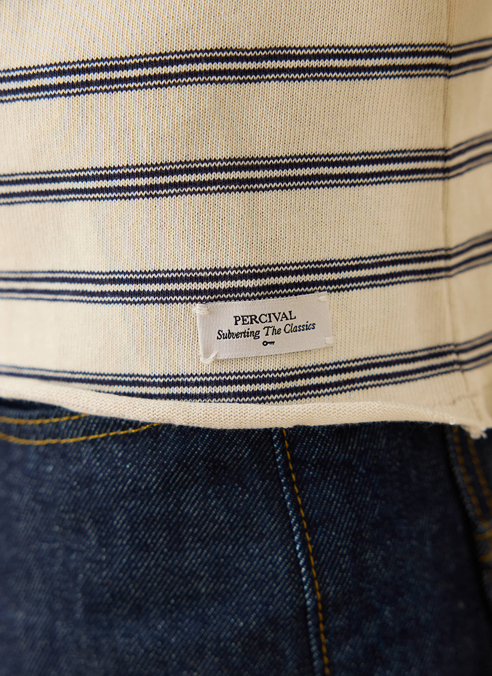 A close-up of the Percival Arlo long-sleeve Breton T-shirt in white stripe, showing the brand label and raw hem.