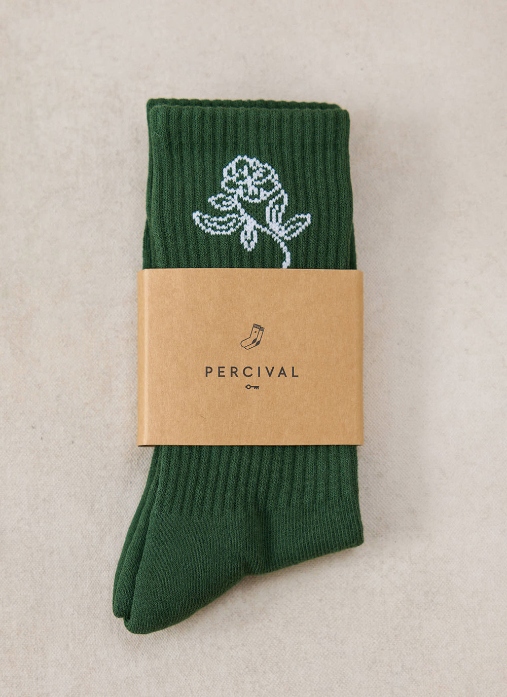 A pair of folded forest green Percival Earl Jacquard socks wrapped with a branded paper band.