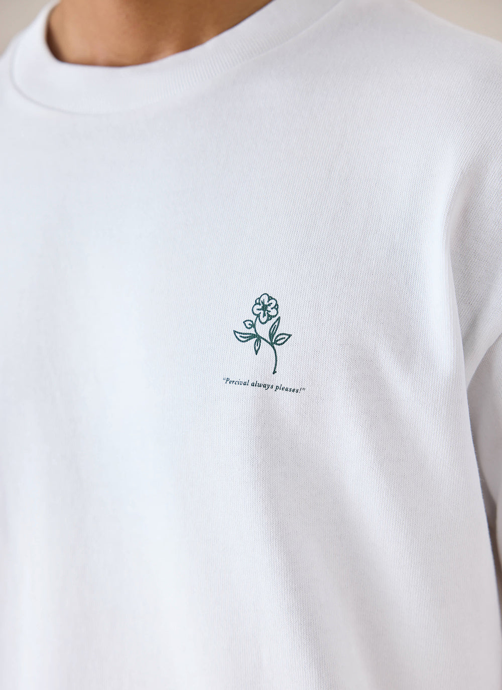 Close-up of white Percival organic cotton t-shirt featuring a small floral chest graphic.