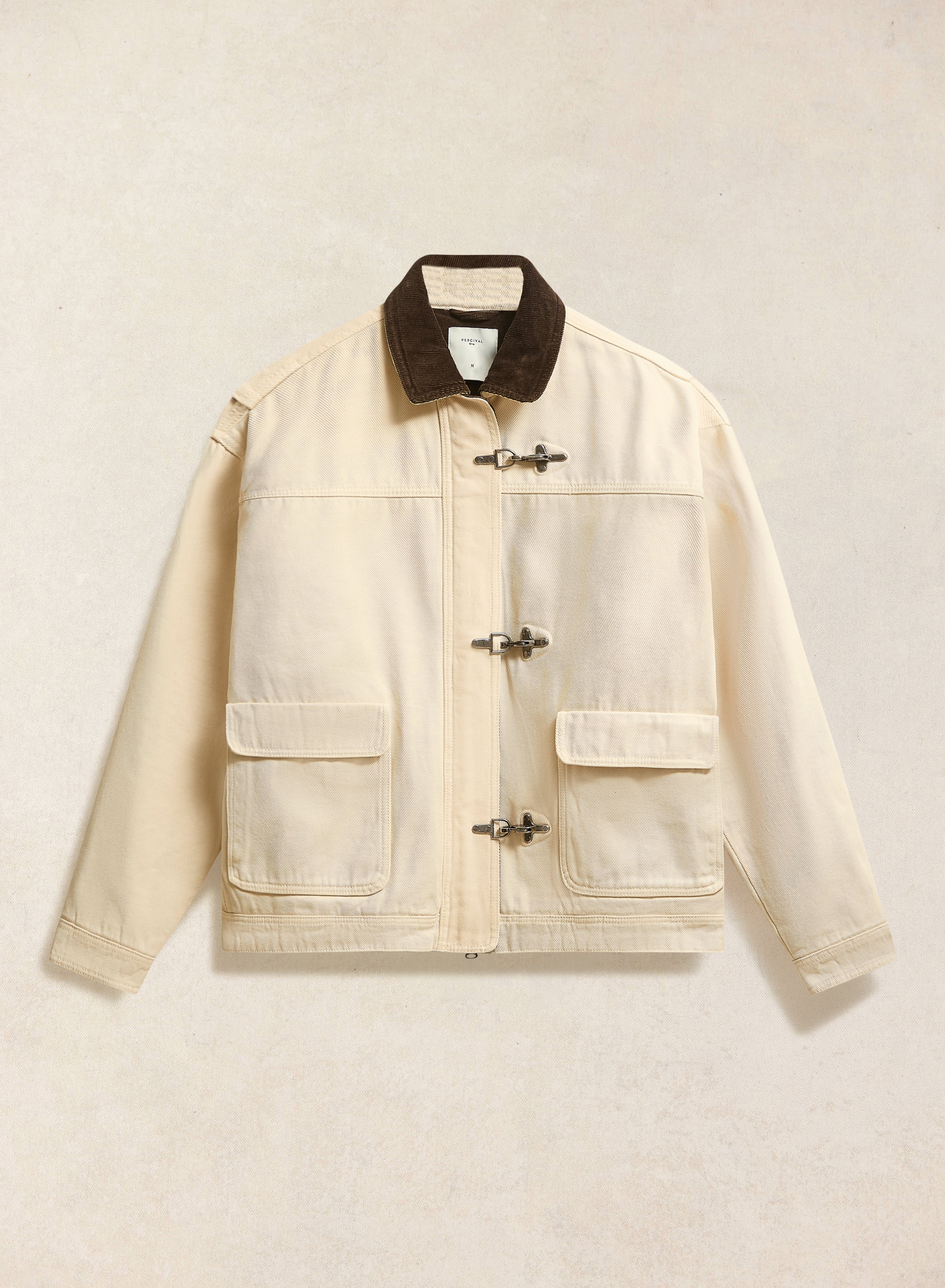 The Percival Fontane Fireman Clasp Jacket in cream, shown flat against a neutral background with a contrast cord collar.