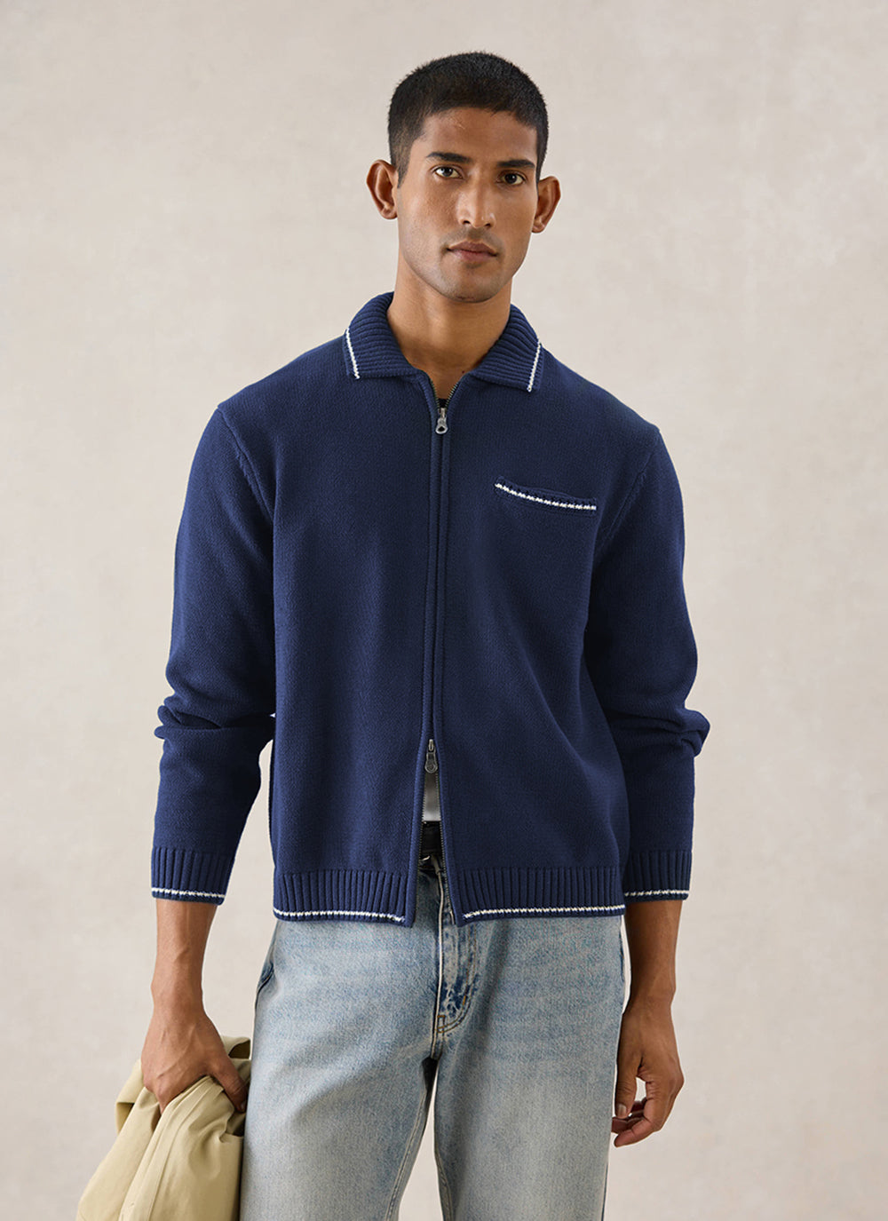 A model wears the navy Percival Gardner zip cardigan in cotton with contrast stitching, paired with jeans.