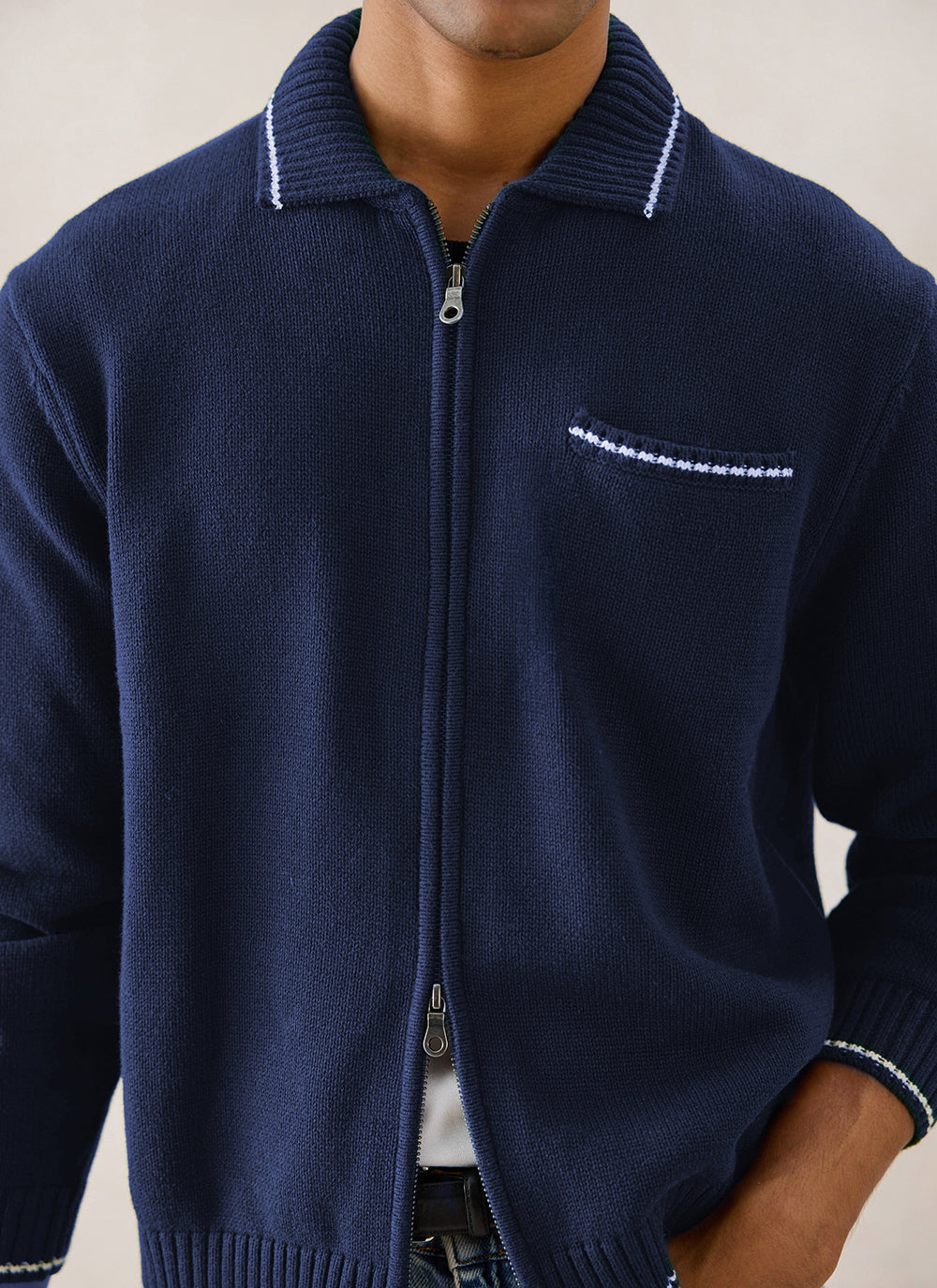 Close-up of a navy blue Percival Gardner cotton zip cardigan on a model, highlighting the two-way zip and chest pocket.