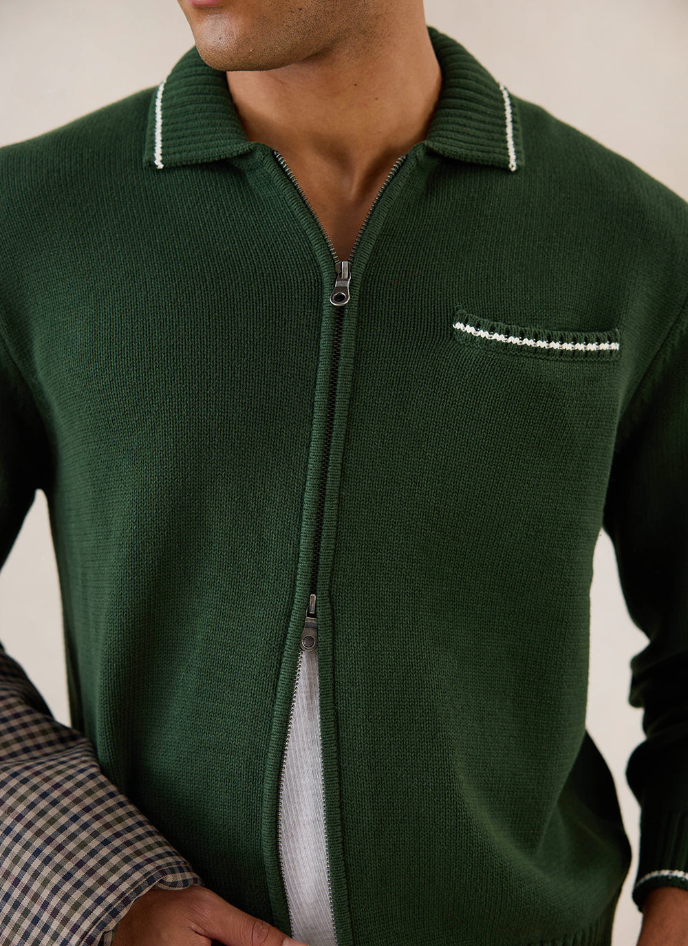 Close-up of model wearing the forest green Percival Gardner dense knitted zip cardigan with contrast tipping.