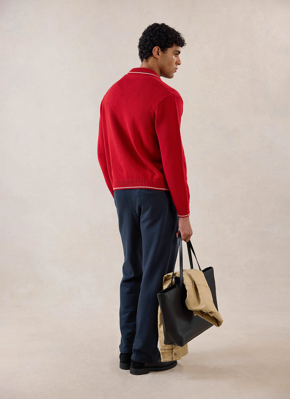 Percival red cotton knit zip cardigan with contrast stitch detailing, shown from behind on a model holding a black tote bag.