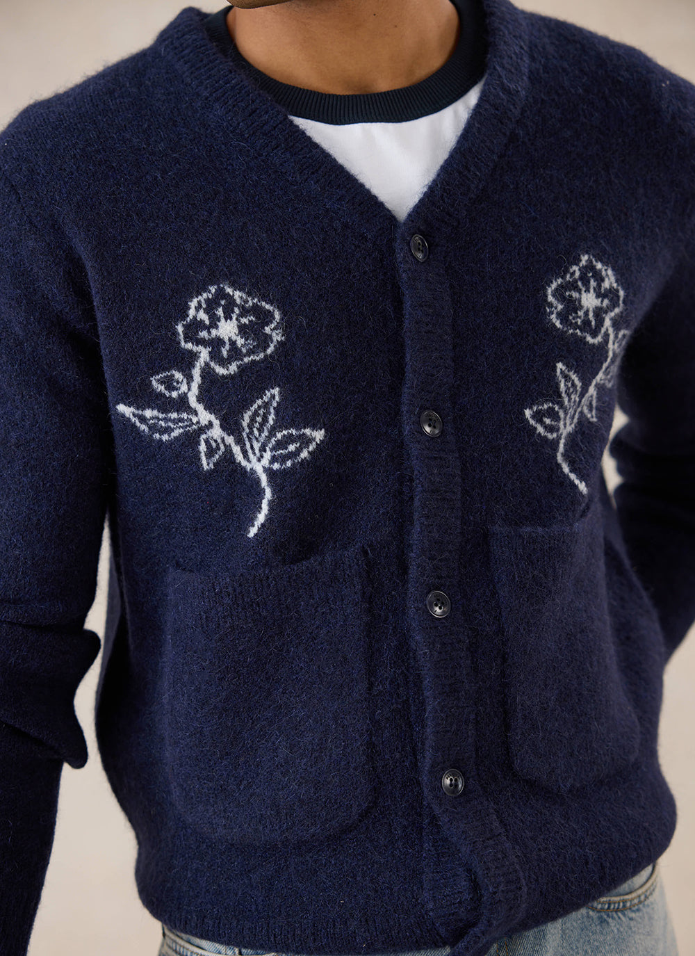 Close-up of a model wearing the navy Percival Gibson Boxy Cardigan, highlighting the white floral knit pattern.