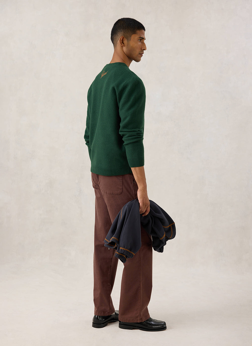 Model wearing the Guinness x Percival forest green wool jumper, showing back neck embroidery.
