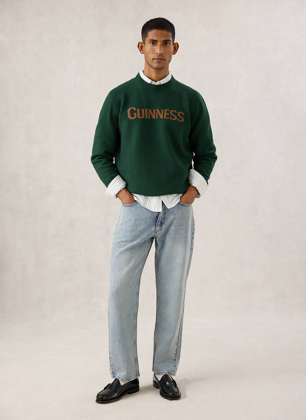 Model wearing the Guinness x Percival forest green merino wool jumper with the contrast jacquard logo across the chest.