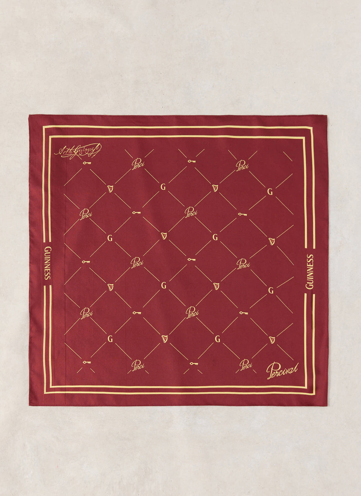 The Guinness x Percival burgundy silk neckerchief flat-laid, showing the gold print and border.