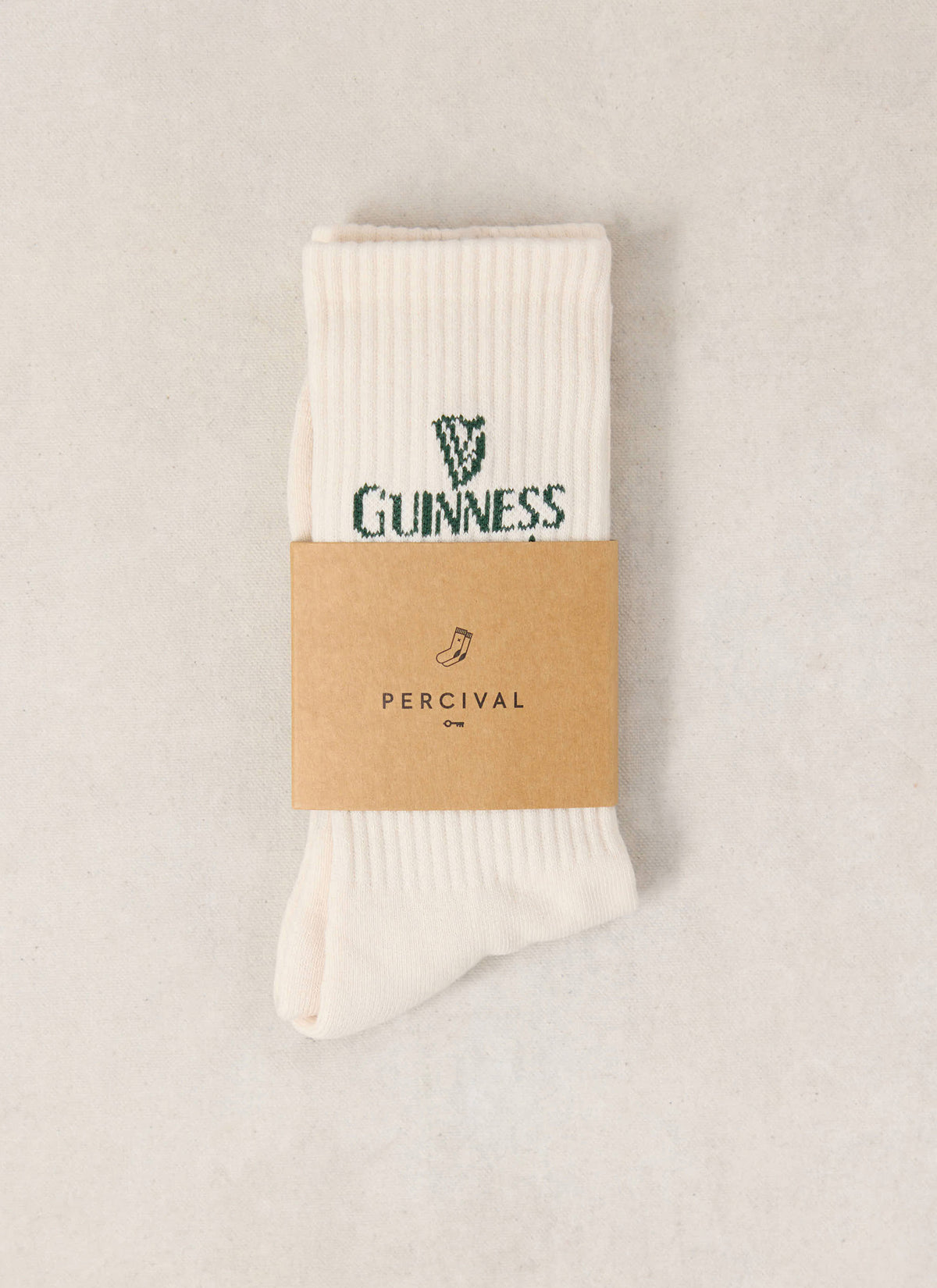 The Guinness x Percival cream ribbed crew socks featuring green branding and a branded paper band.