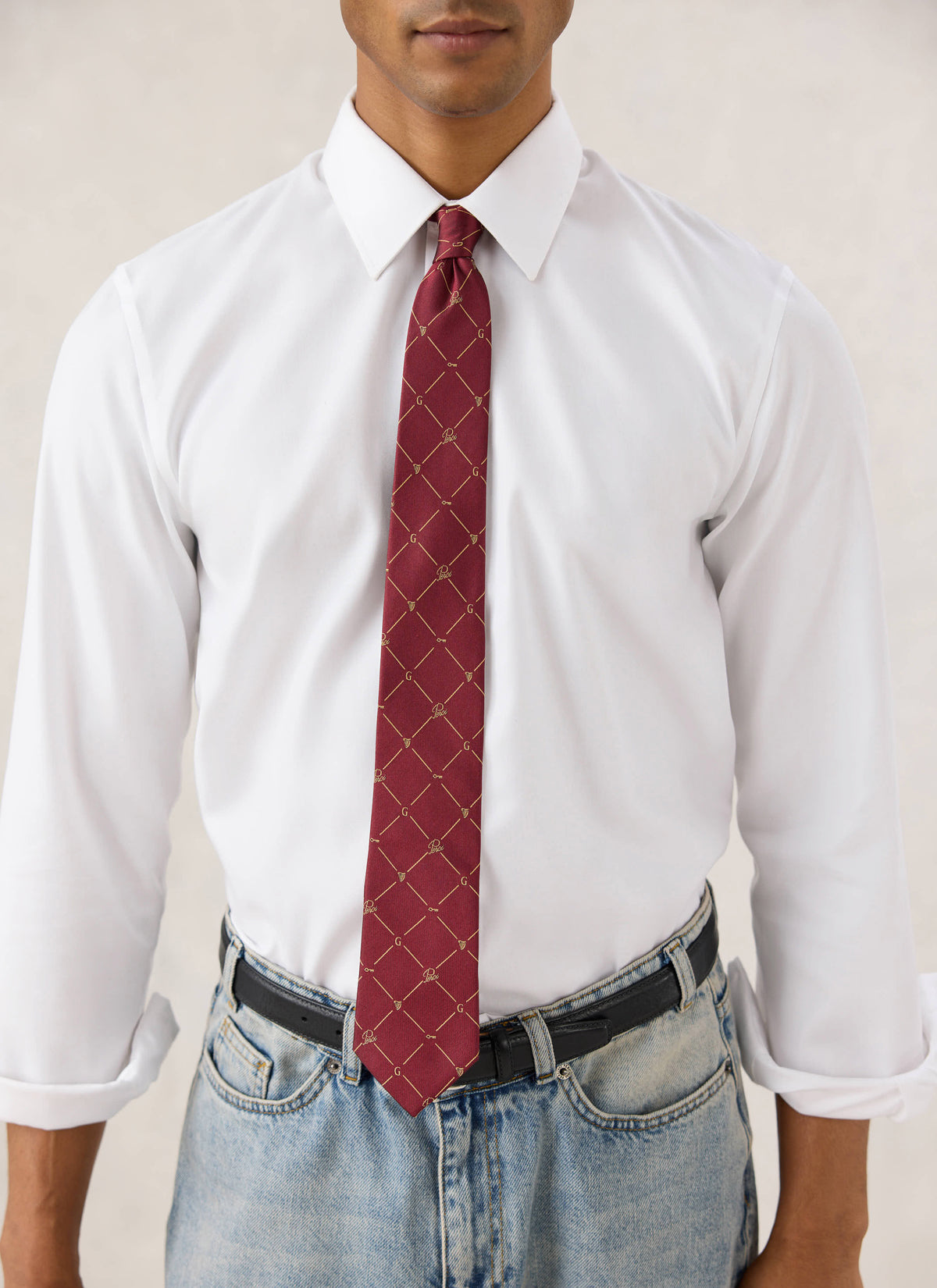 Model wearing the burgundy Guinness x Percival silk tie with a geometric motif, styled with a white shirt and jeans.