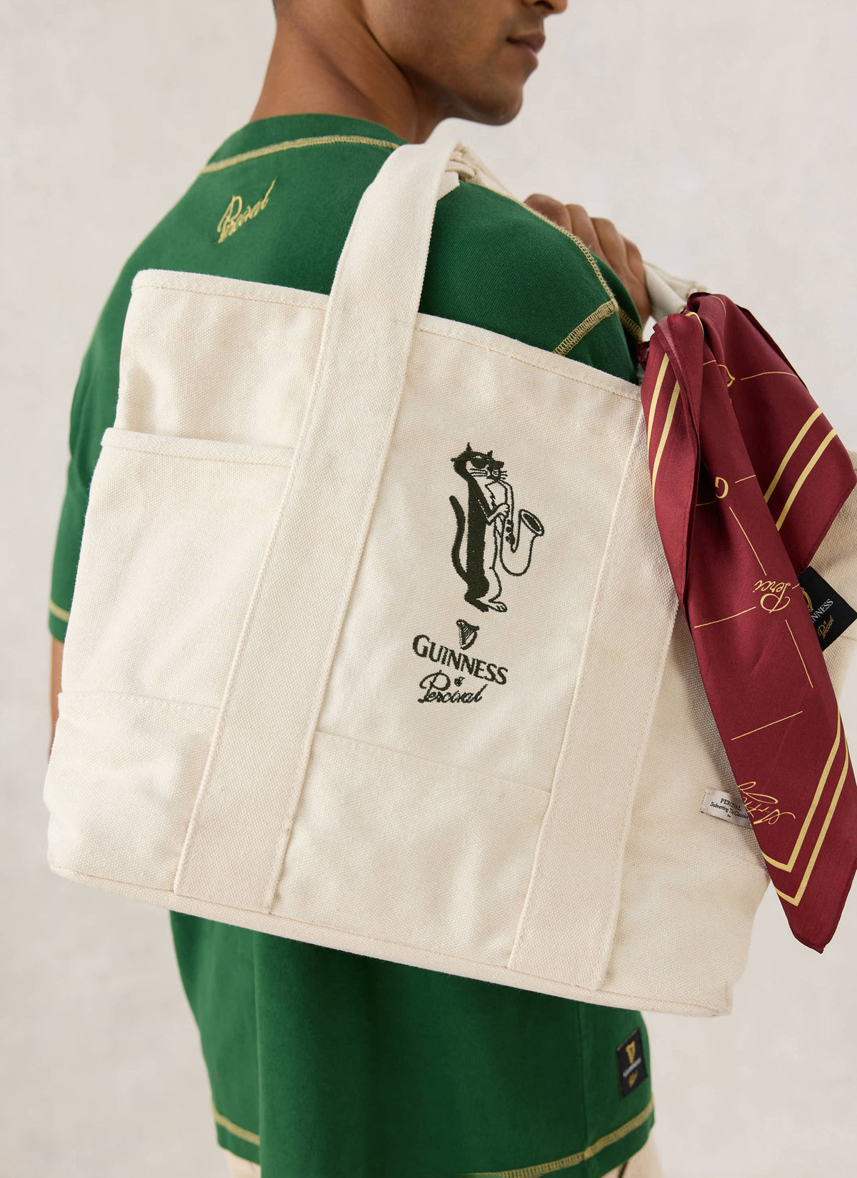 A model wearing the cream Guinness x Percival saxophonist embroidered tote bag slung over the shoulder.