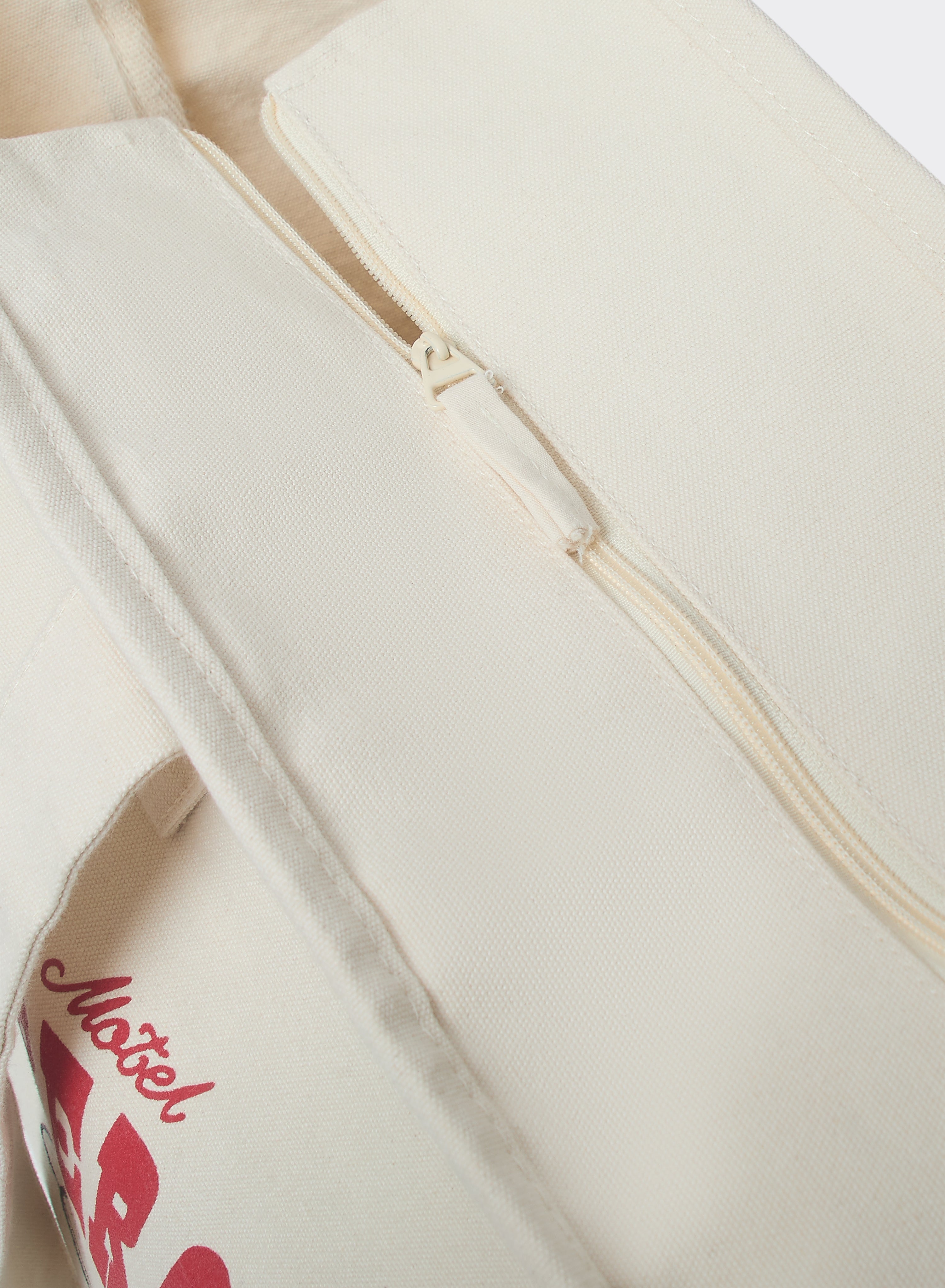The Percival Gordon Large Tote Bag in cream cotton, showing a close-up of the zip closure and red graphic detail.