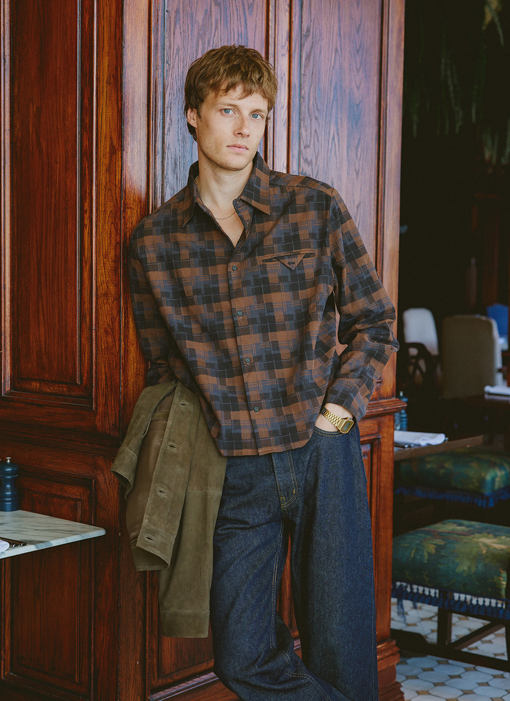 A model wears the Percival brown check Hinsley boxy shirt with raw denim jeans and a suede jacket.