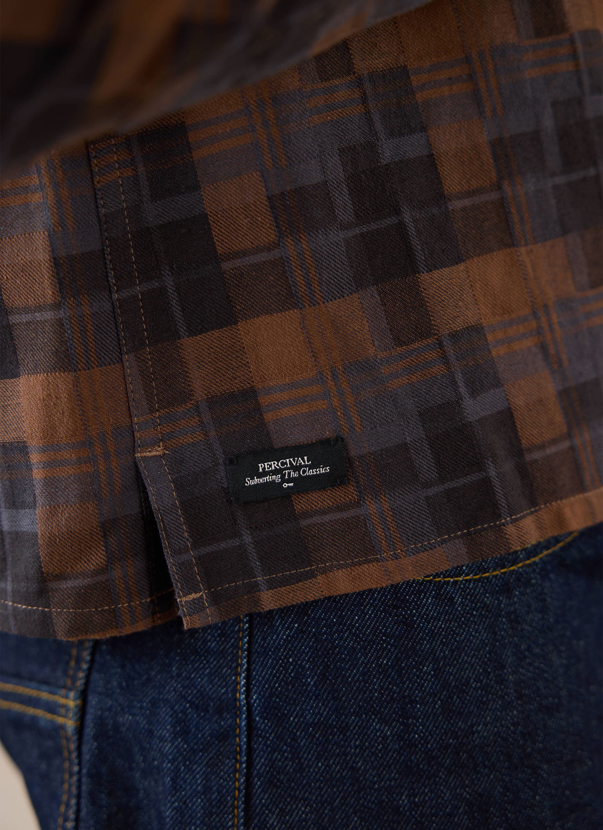 Close-up of the brown check Percival shirt, showing the brand label detail.