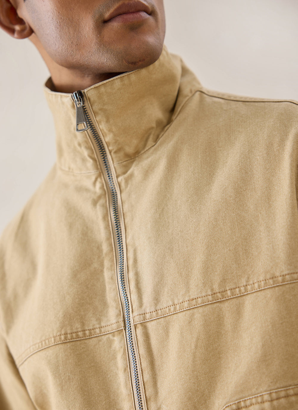 A close-up of a model wearing the cream Percival Jackson Harrington Jacket, highlighting the funnel neck and zip detail.