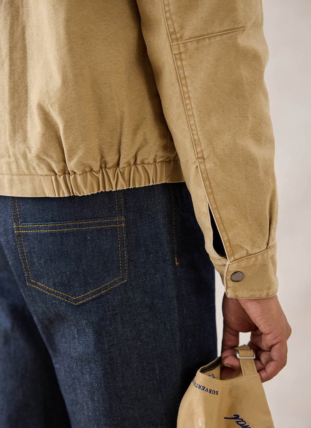 Close-up of a model wearing the cream Percival Jackson Boxy Harrington Jacket and dark jeans.
