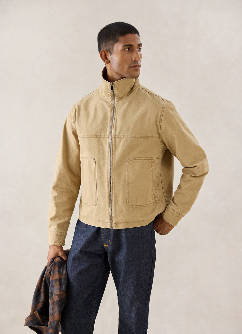 A model wears the cream Percival Jackson Boxy Harrington Jacket and dark jeans in a studio shot.