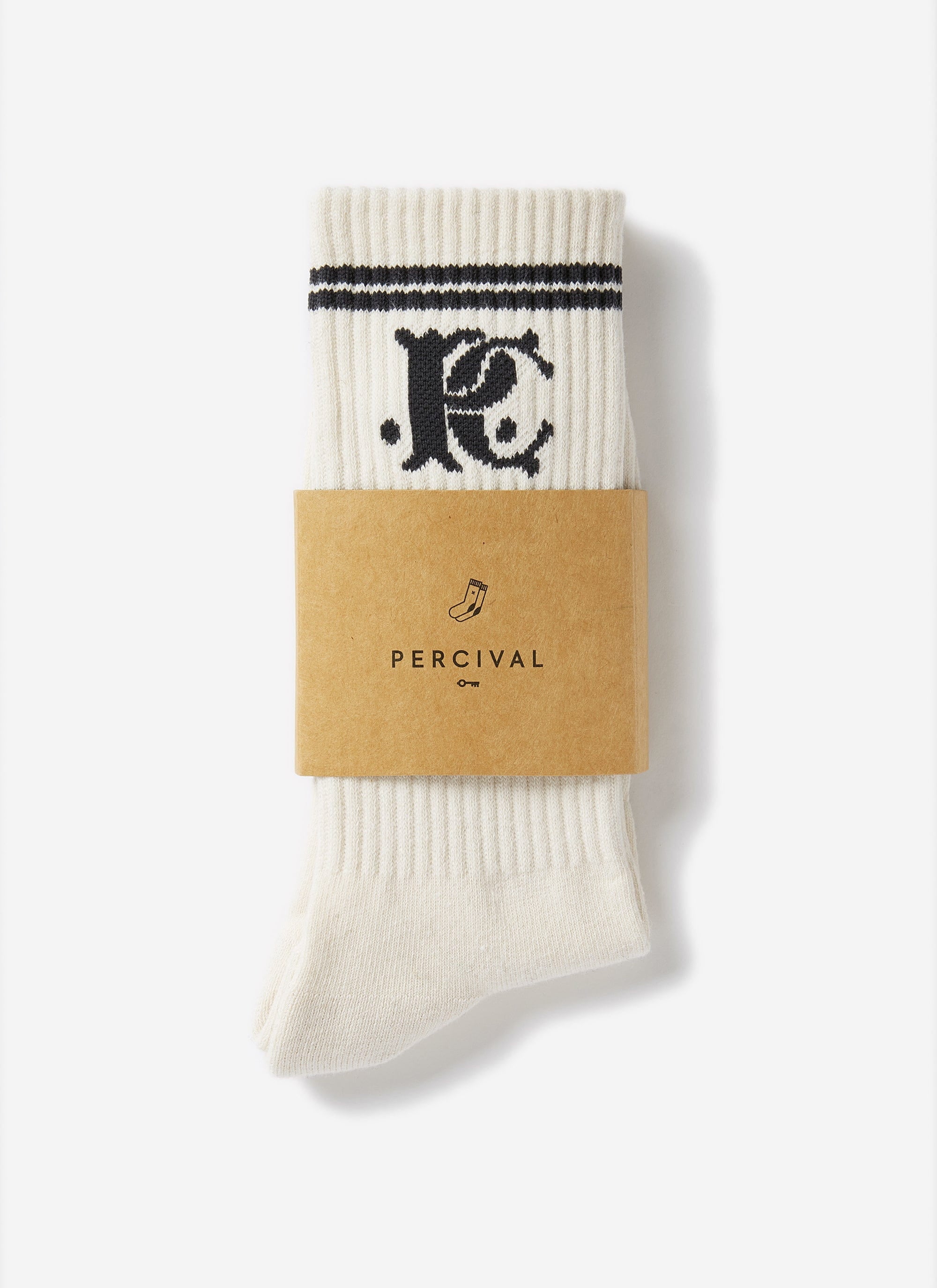The Champion x Percival Jacquard Socks in white, with black logo and stripes, folded and presented in a Percival sleeve.