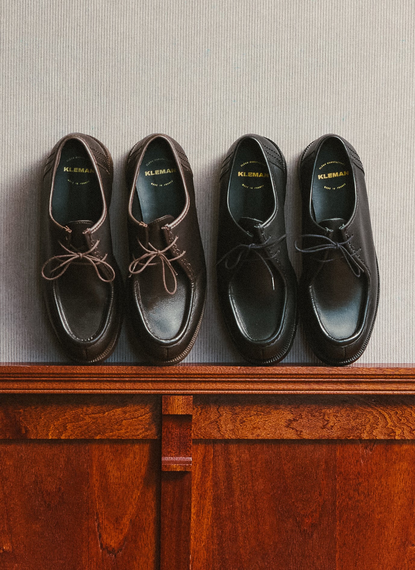 Two pairs of Percival Kleman Padror shoes in brown and black leather displayed side by side on a wooden surface.