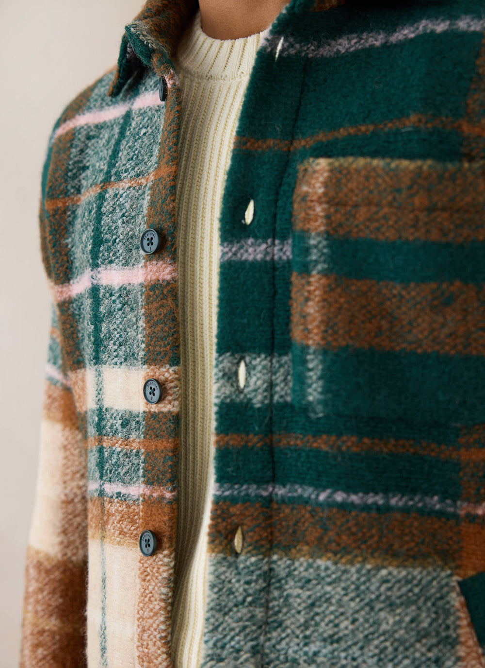 A close-up of a model wearing the multi check Percival Knowles overshirt over a white knitted jumper.