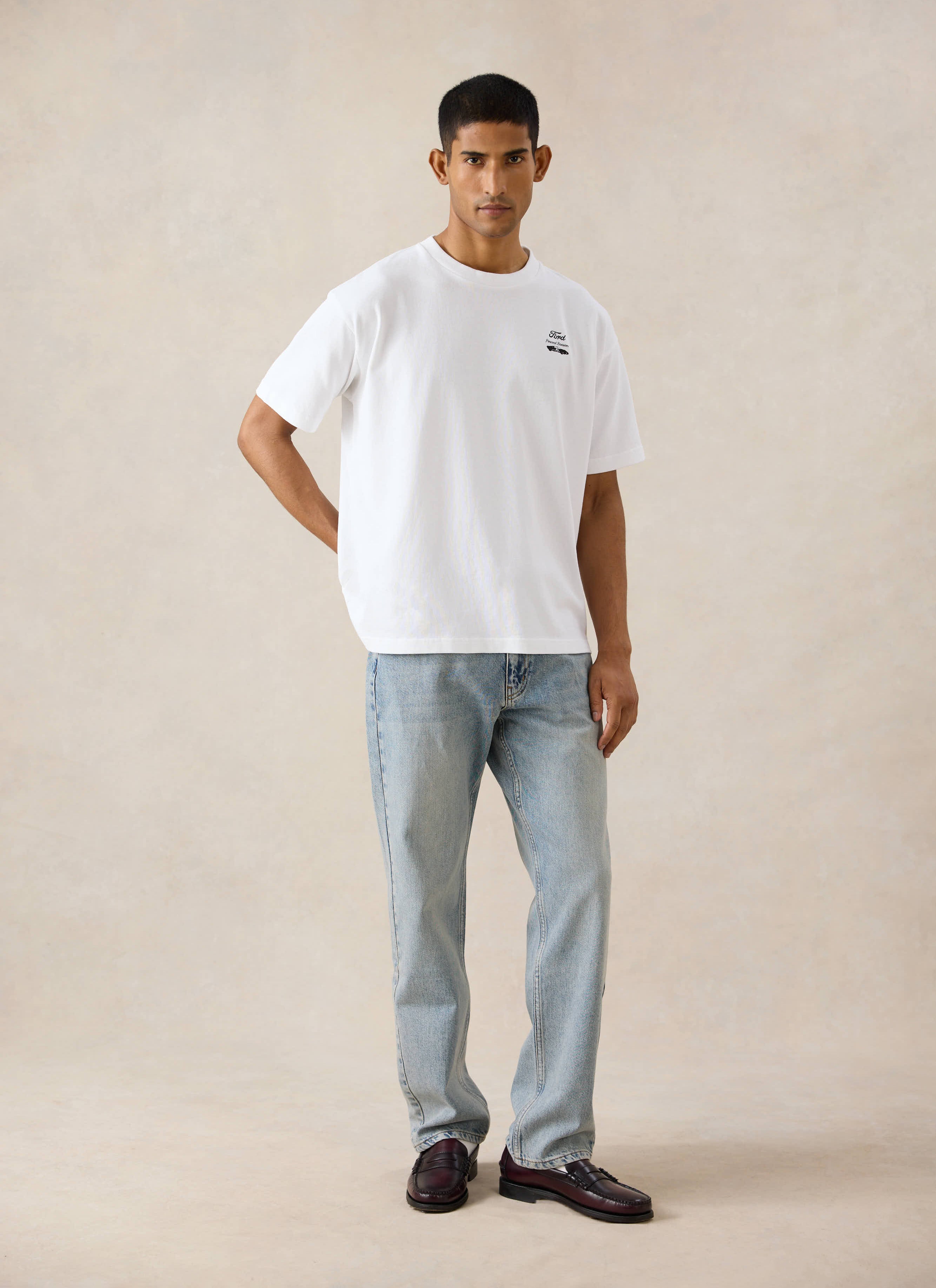 White Percival x Ford Le Mans oversized t-shirt, styled with light wash heritage denim jeans and dark loafers.