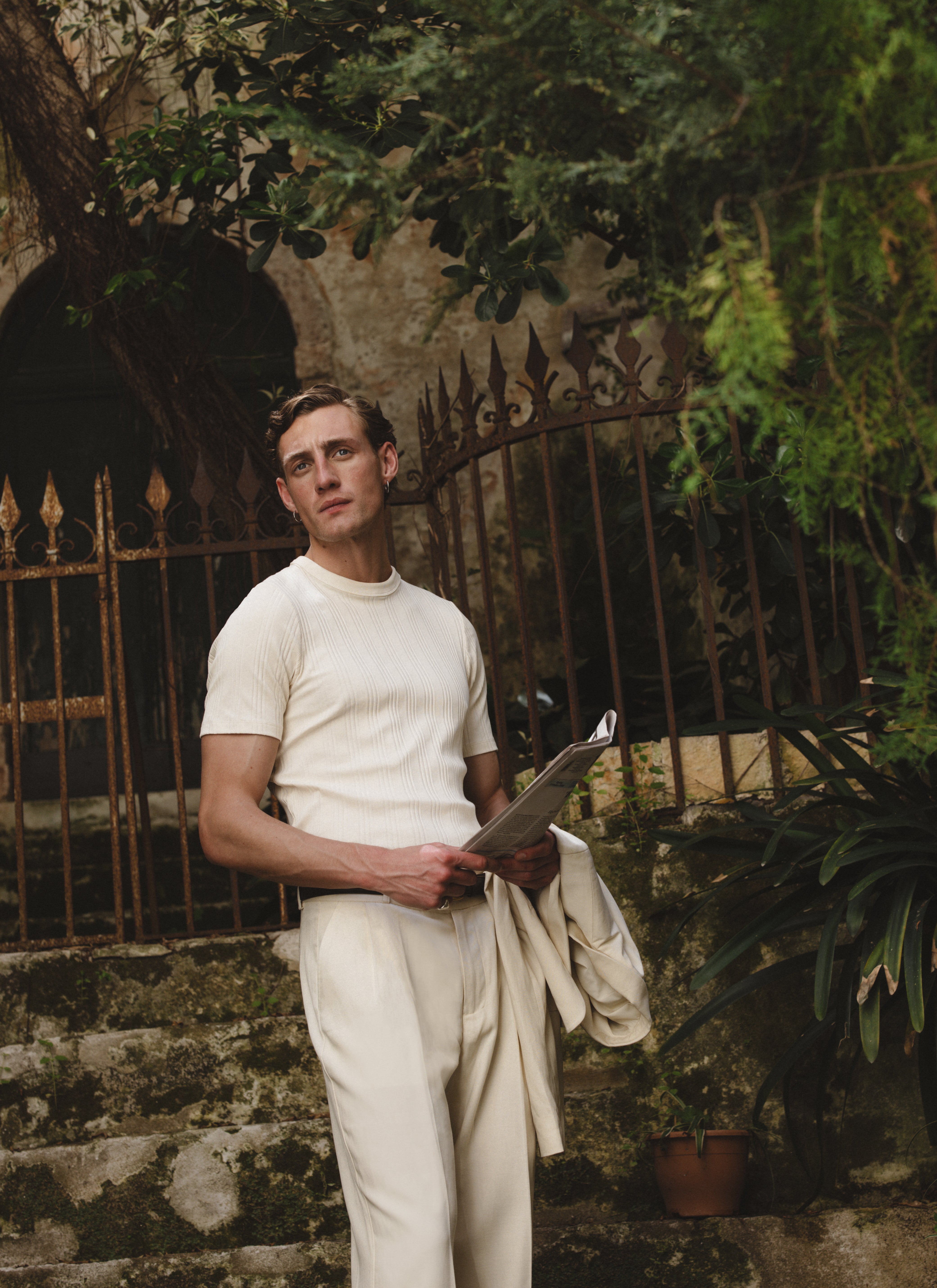 Cream Percival Leon slim ribbed t-shirt in organic cotton, worn by a model in an outdoor garden setting.