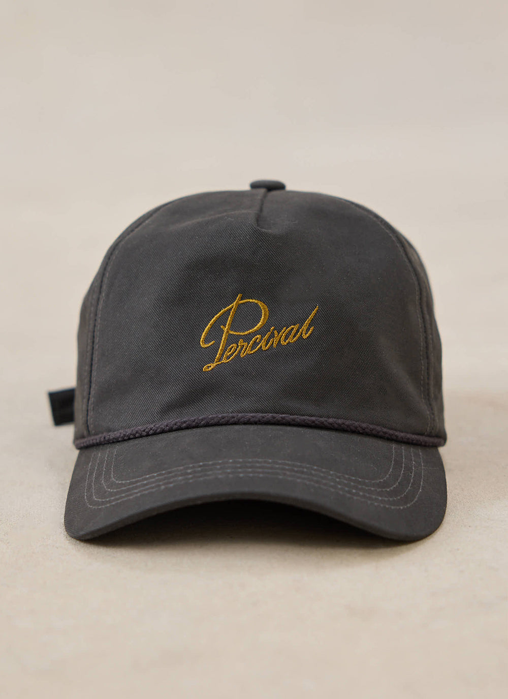 A close-up of the charcoal Percival Luther Soft Trucker Cap with gold embroidery on the front.