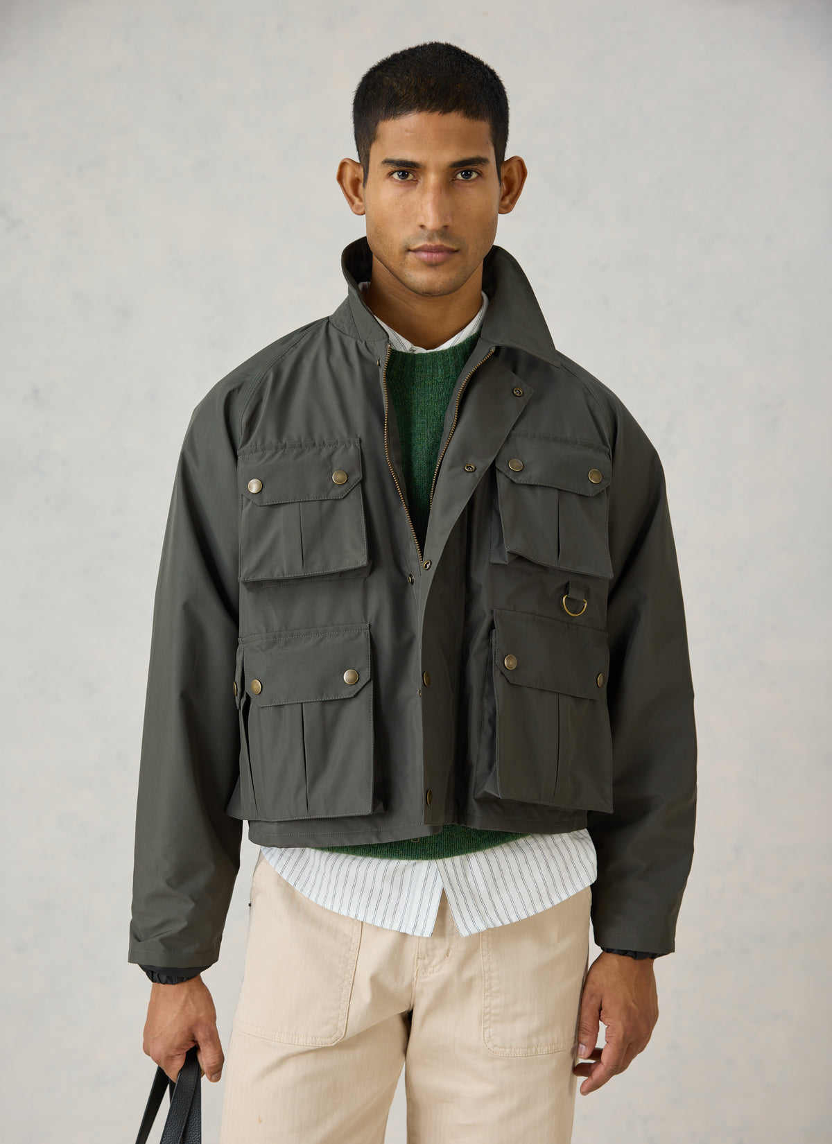 A model wearing the forest green Percival Hunter Jacket, a cropped water-repellent field jacket featuring front pockets.
