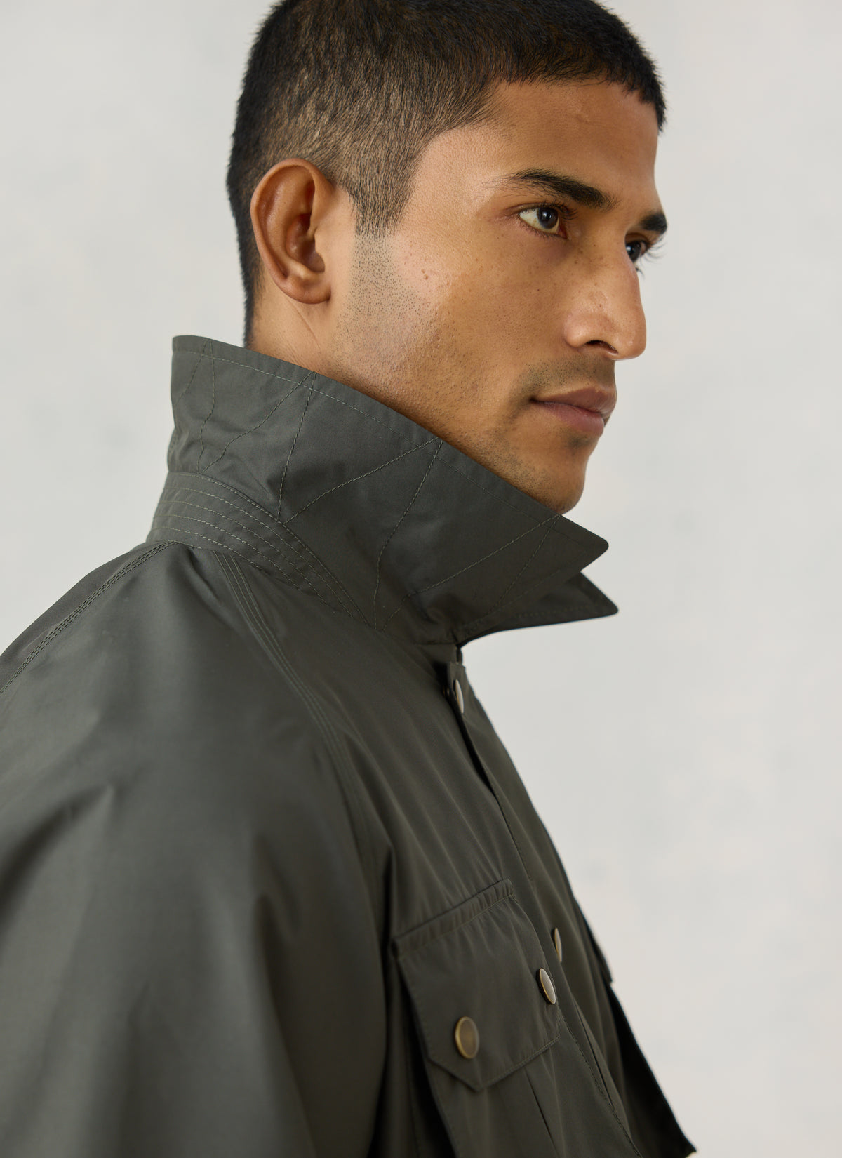 A close-up of a model wearing the forest green Percival Hunter Jacket, highlighting the turned-up stitched collar.