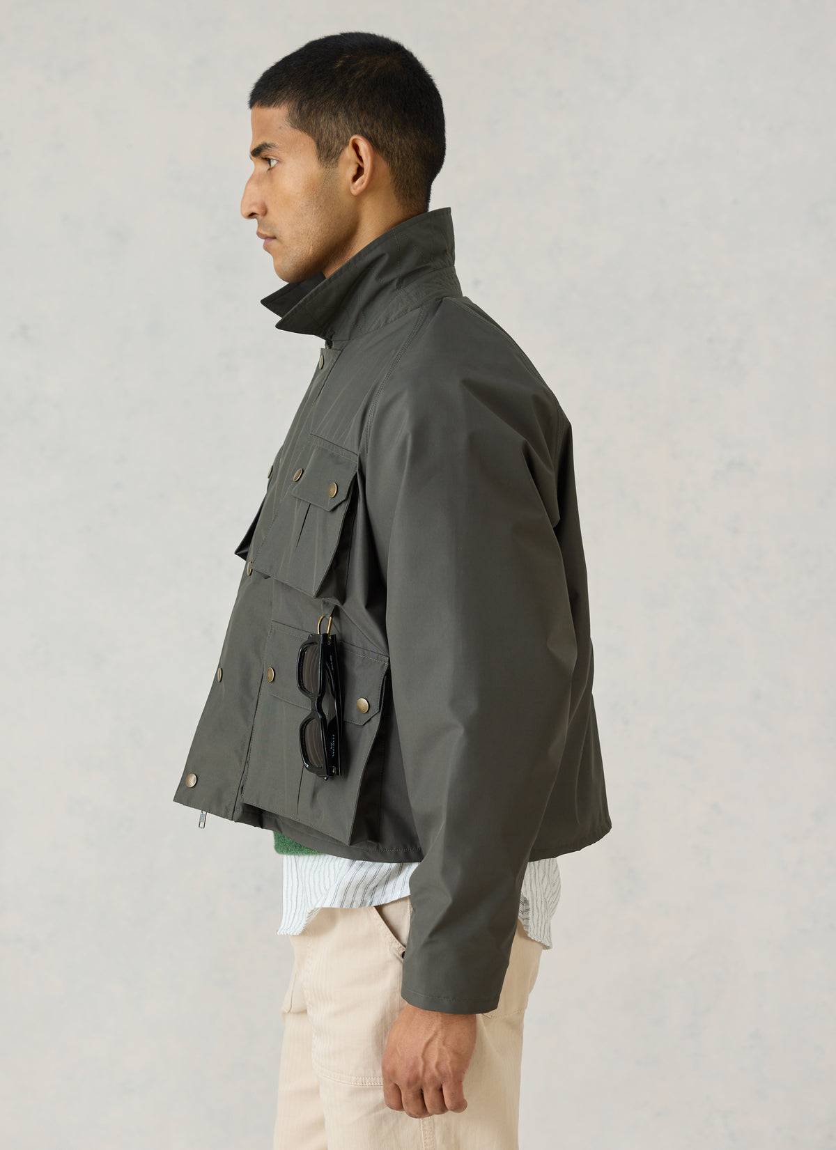 Side profile of a model wearing Percival's forest green Hunter Field Jacket, showing its cropped fit and front pockets.
