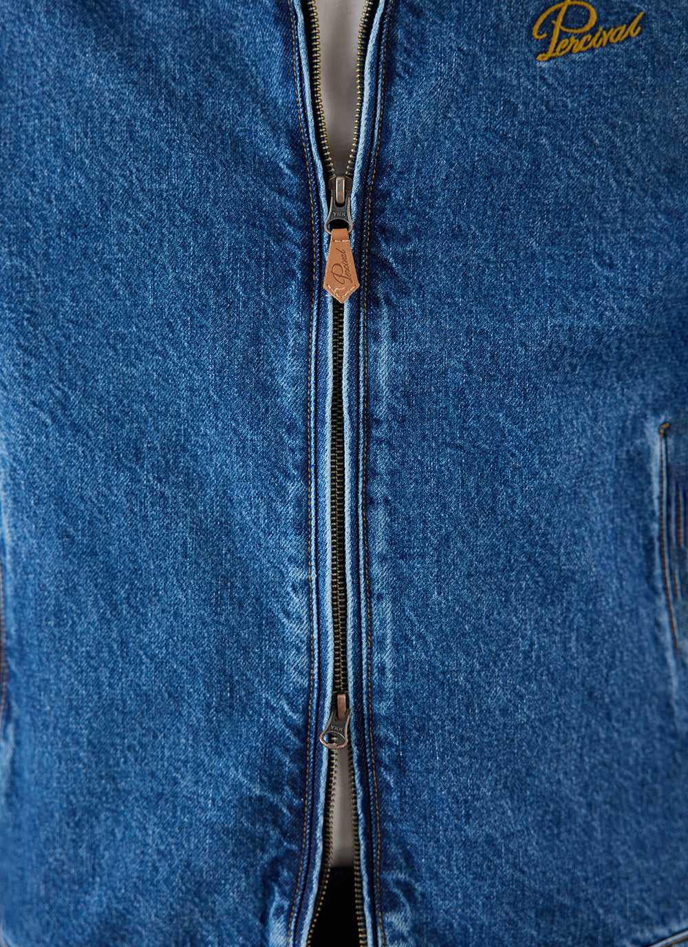 Close-up of the mid wash blue Percival Mackey Zip Jacket showing the zipper and chest embroidery detail.