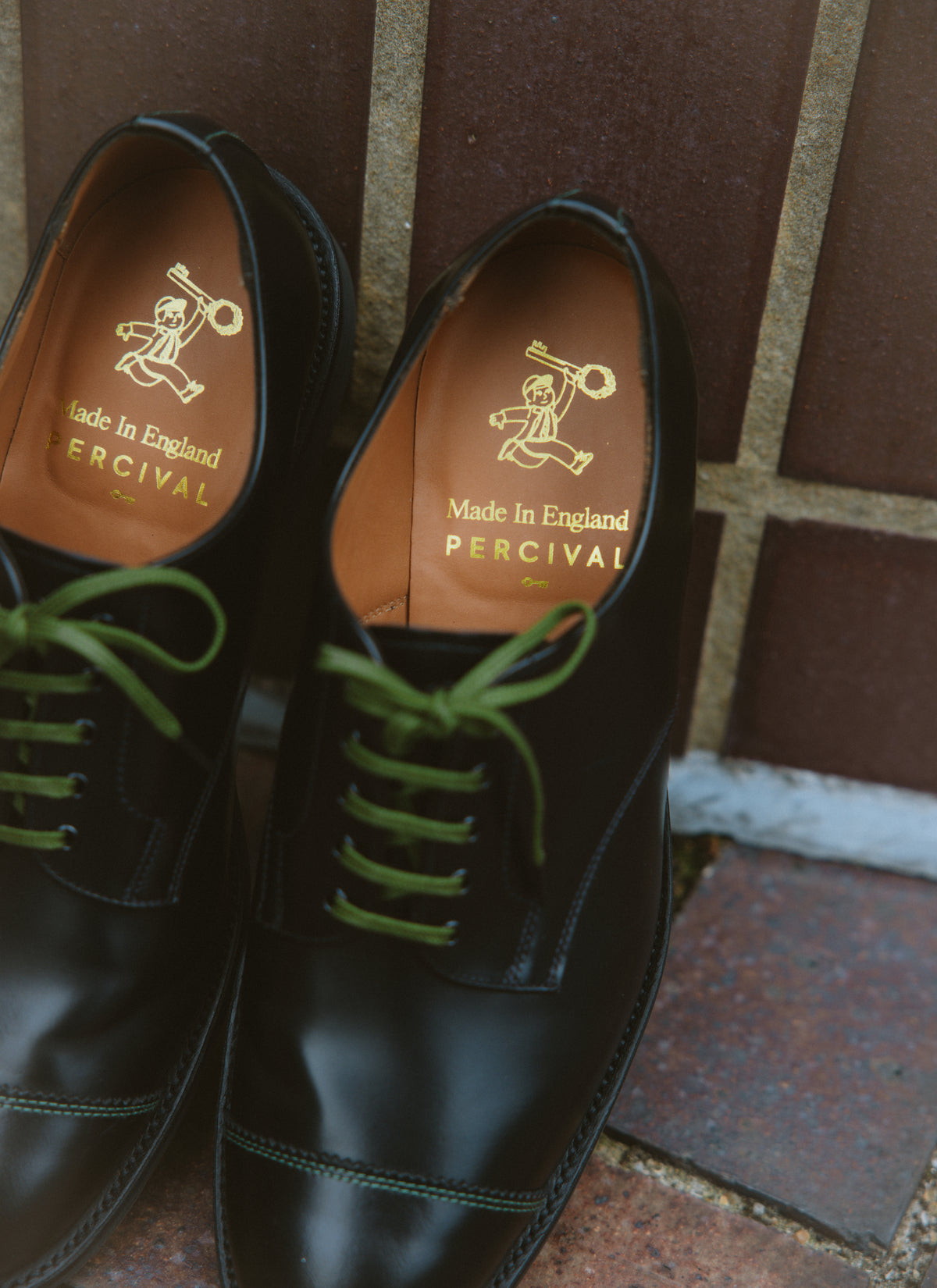 Black leather Derby shoes by Percival featuring military green laces and gold foil branding on the inner insoles.