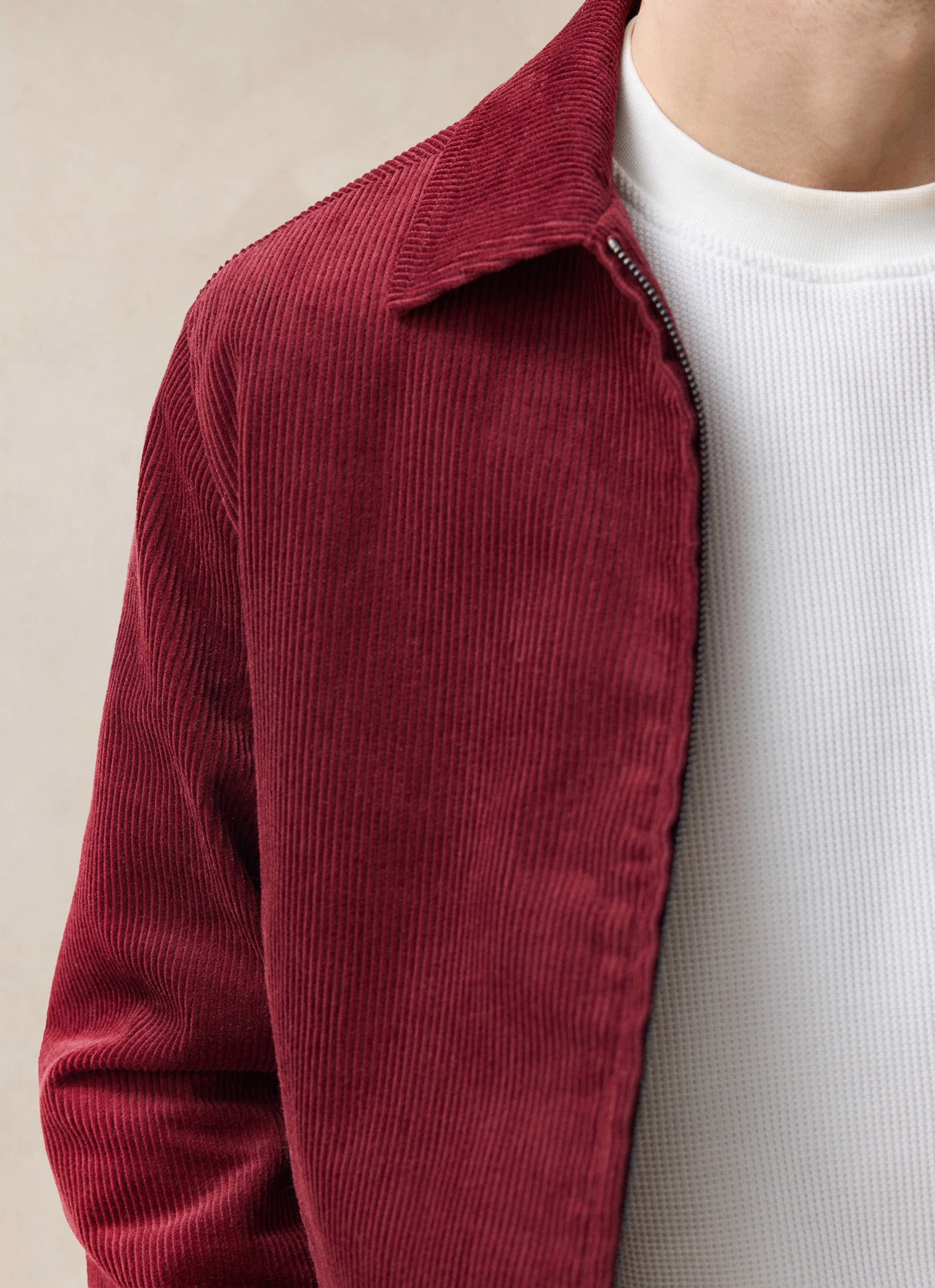 Close-up of a model wearing the burgundy Percival Marcel cord jacket over a white textured t-shirt.