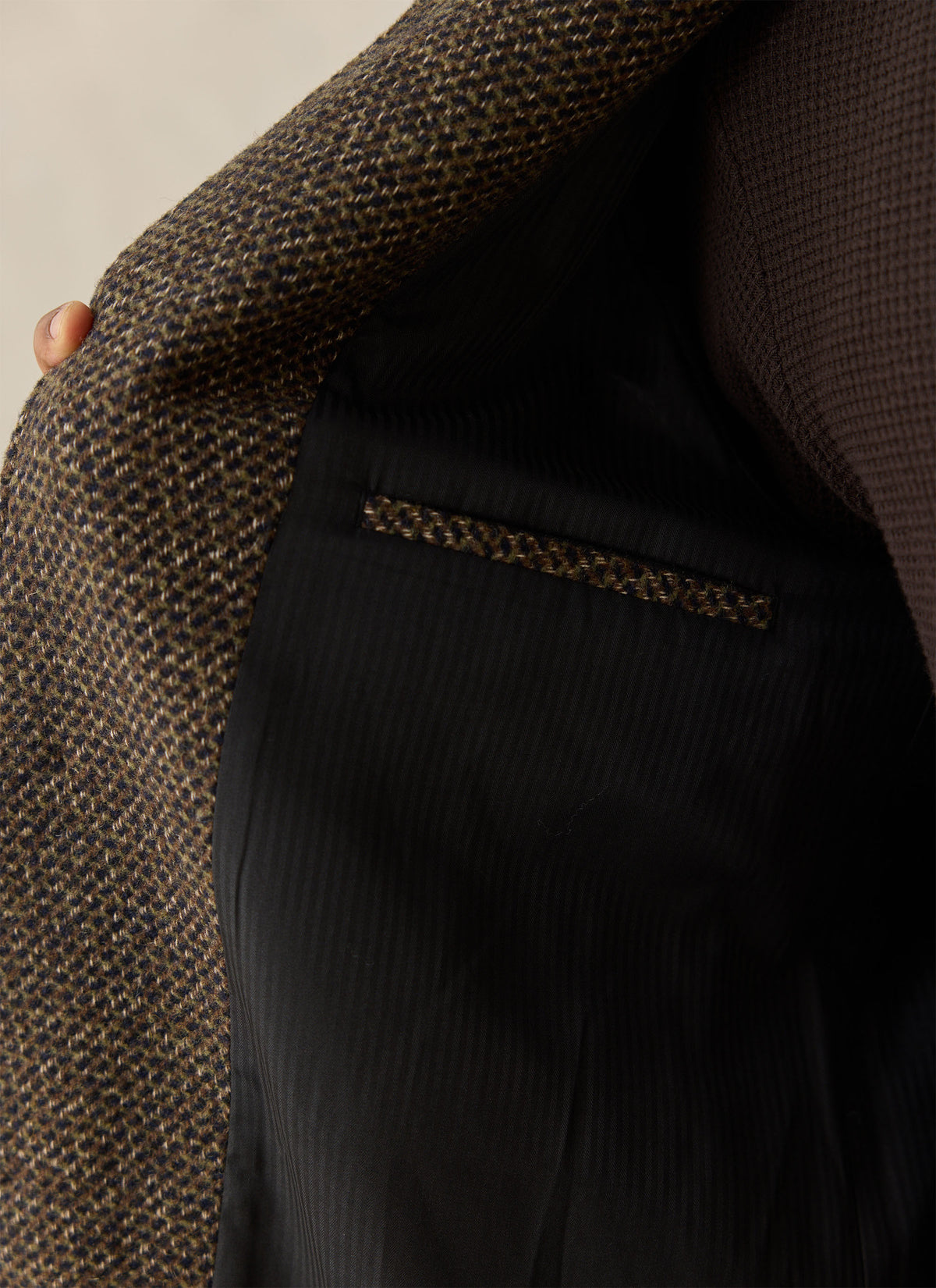 A close-up of the Percival brown fleck wool-blend Mason car coat showing the dark lining and internal pocket detail.