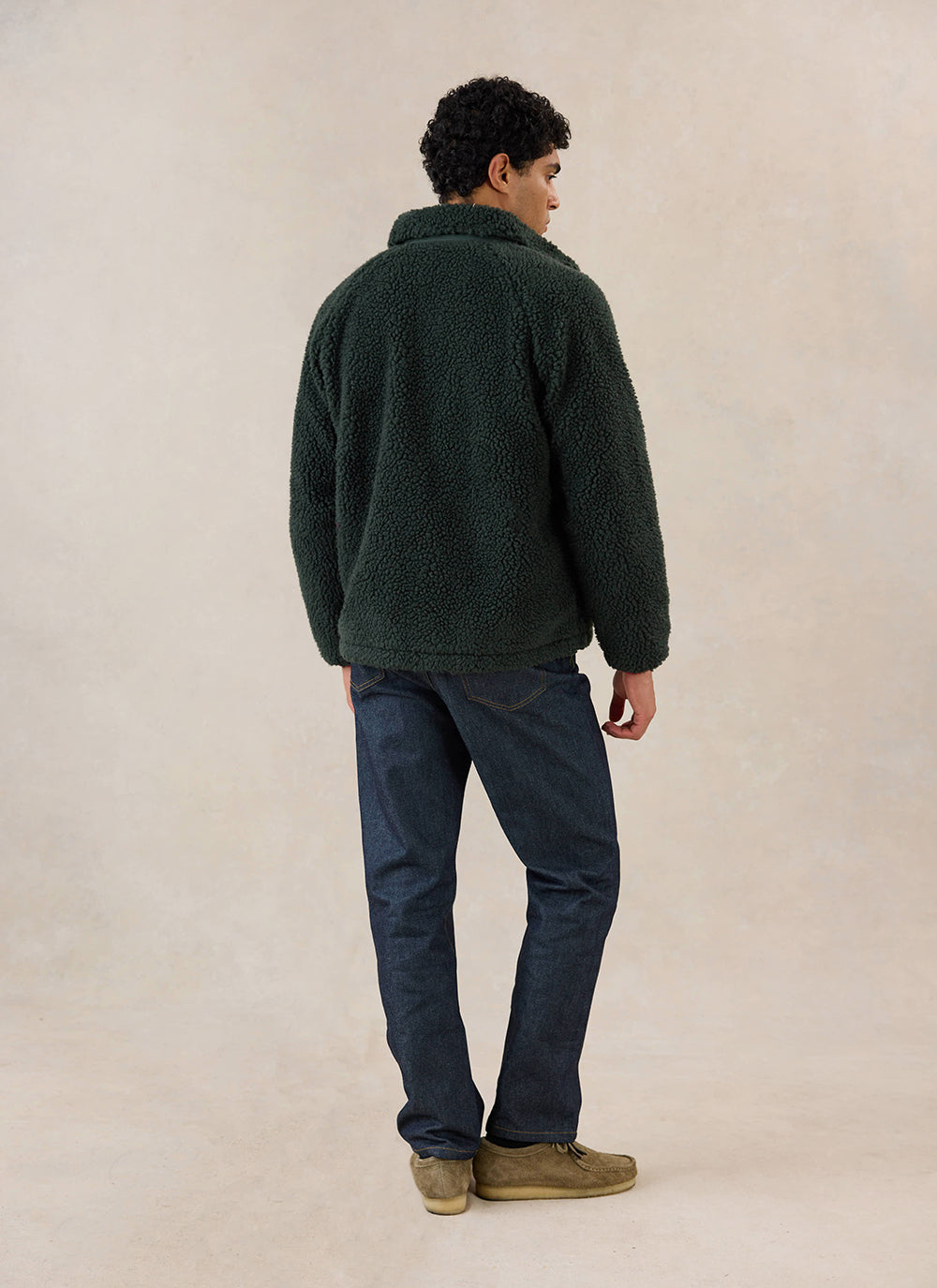 A model shown from the back wearing the Percival forest green wool fleece jacket and dark denim jeans in a studio setting.