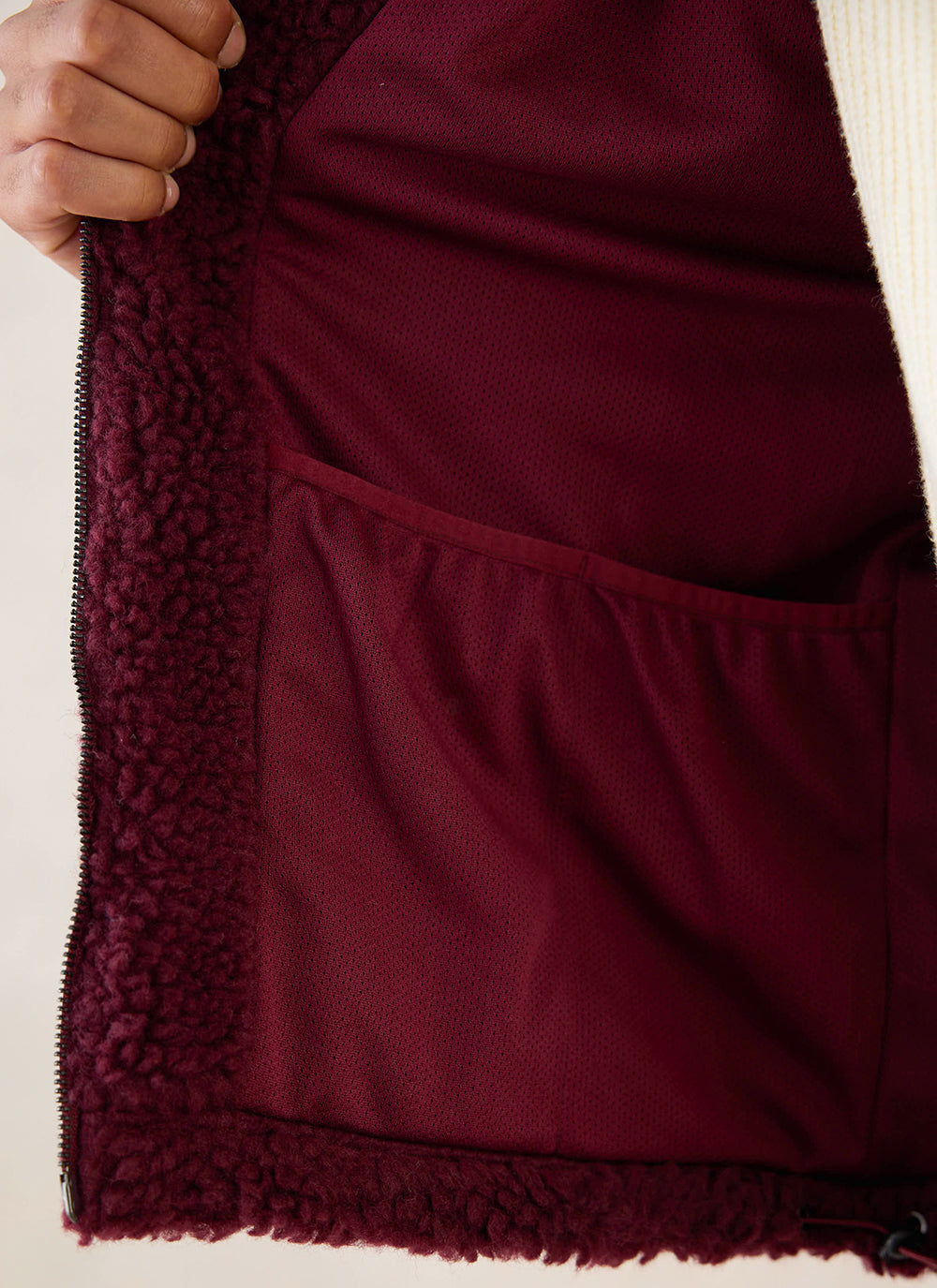 A close-up of the interior lining and pocket of the burgundy wool blend fleece jacket from Percival.