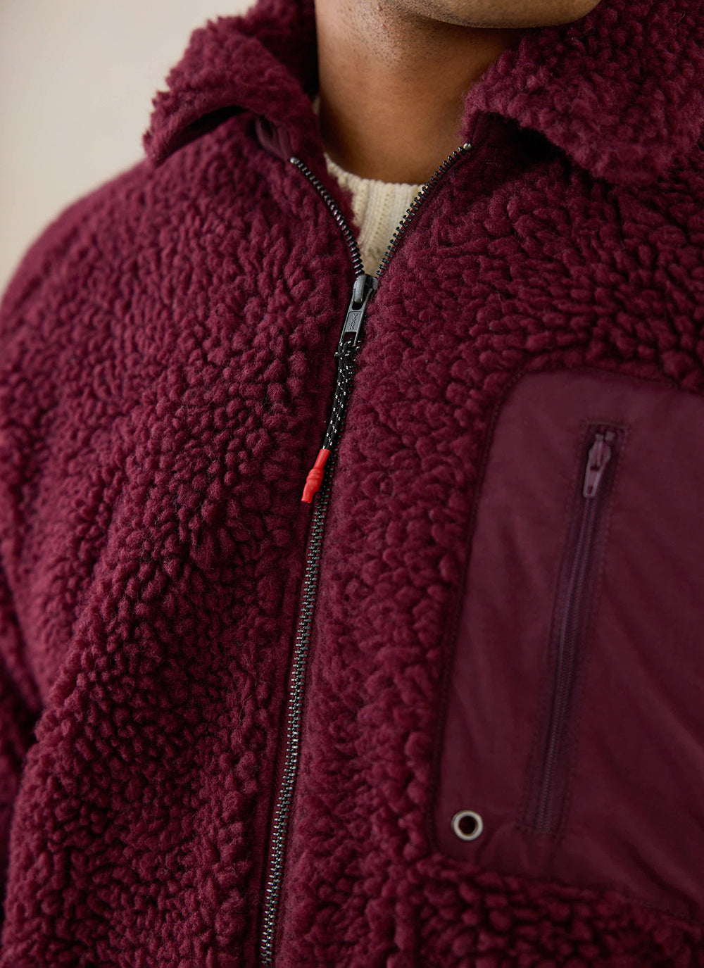A close-up of the burgundy Percival wool fleece jacket, showing the zip and contrast chest pocket details.